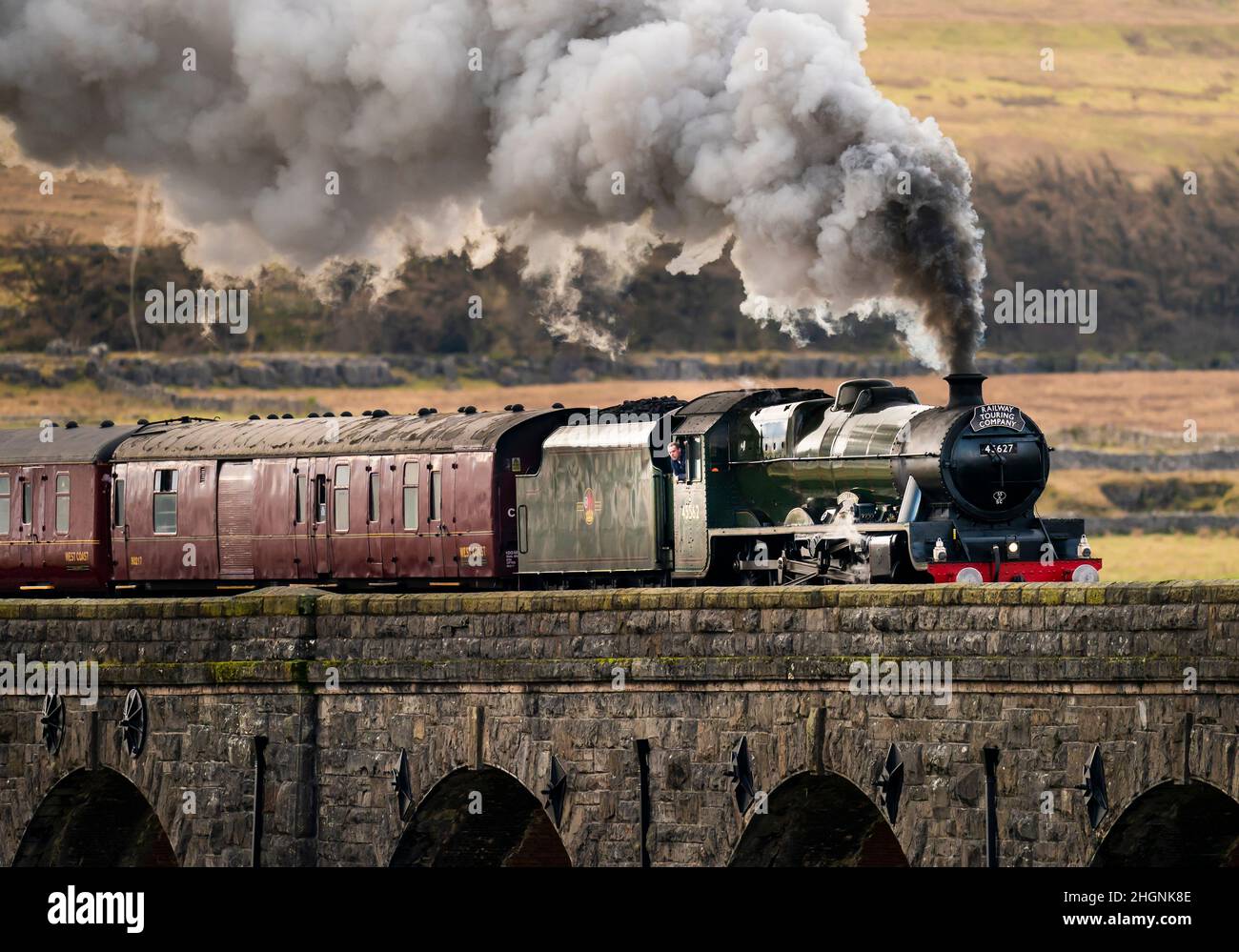 Una persona si affaccia fuori dalla vedova del Winter Cumbrian Mountain Express, la prima linea principale della società treno trainato a vapore del 2022, attraversa Ribblehead Viaduct nel Parco Nazionale Yorkshire Dales. Data foto: Sabato 22 gennaio 2022. Foto Stock