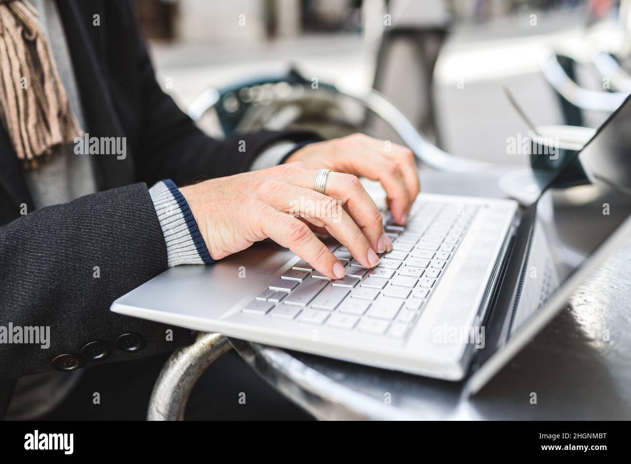 Uomo irriconoscibile che digita e naviga i dati sul laptop mentre si siede al tavolo e si lavora in remoto nella caffetteria della strada Foto Stock