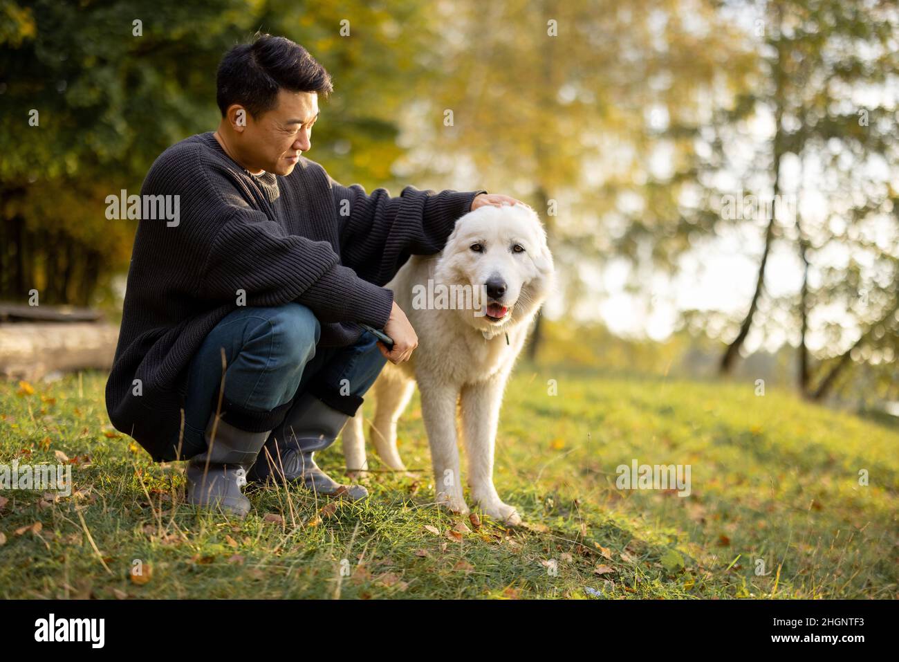 Uomo carezza cane e guardare via in natura in autunno Foto Stock