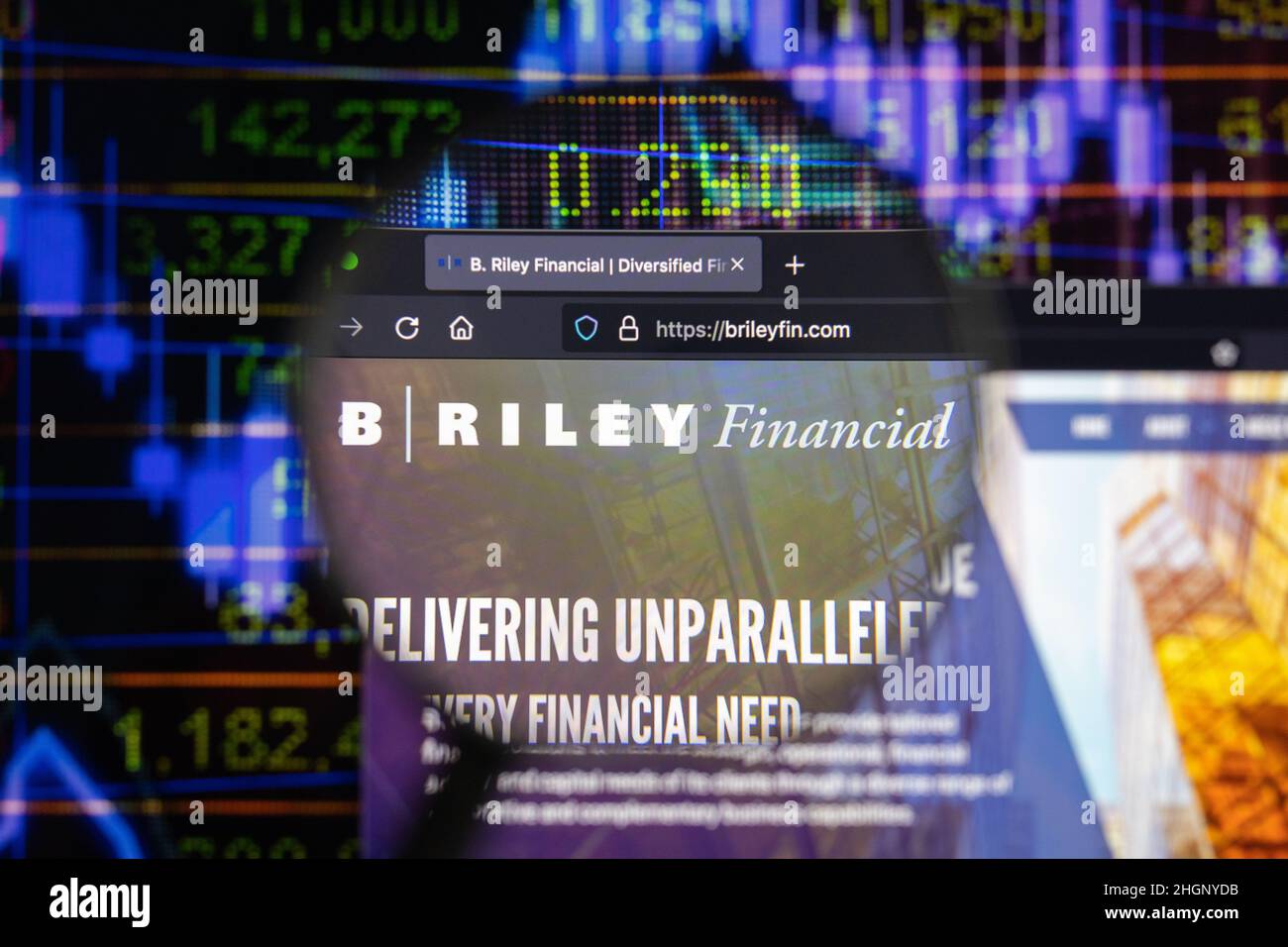 B. Riley Financial, Inc. Logo aziendale su un sito web con sviluppi del mercato azionario sfocati in background, visto su uno schermo del computer Foto Stock