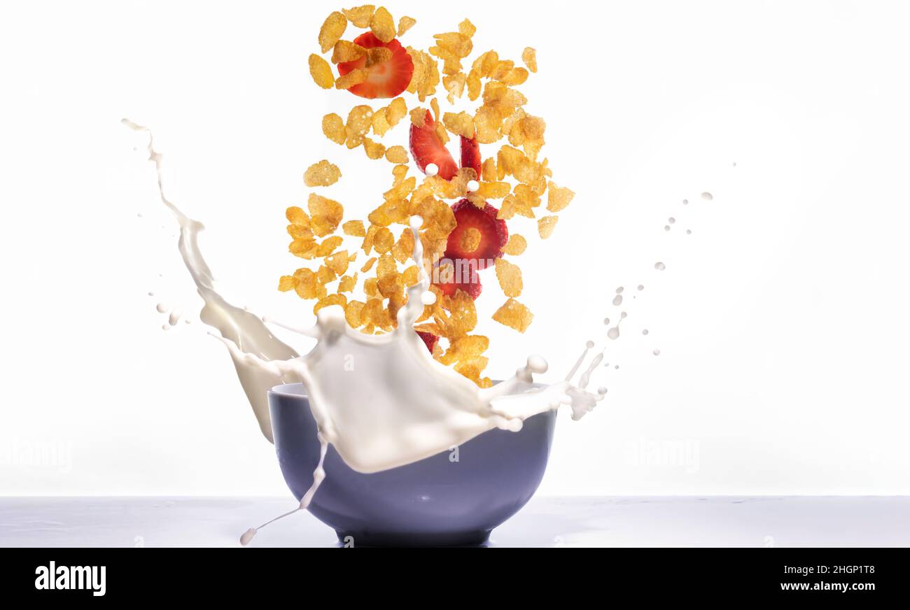Corn fiocchi con fragole cadere e spruzzare in una ciotola con latte Foto Stock