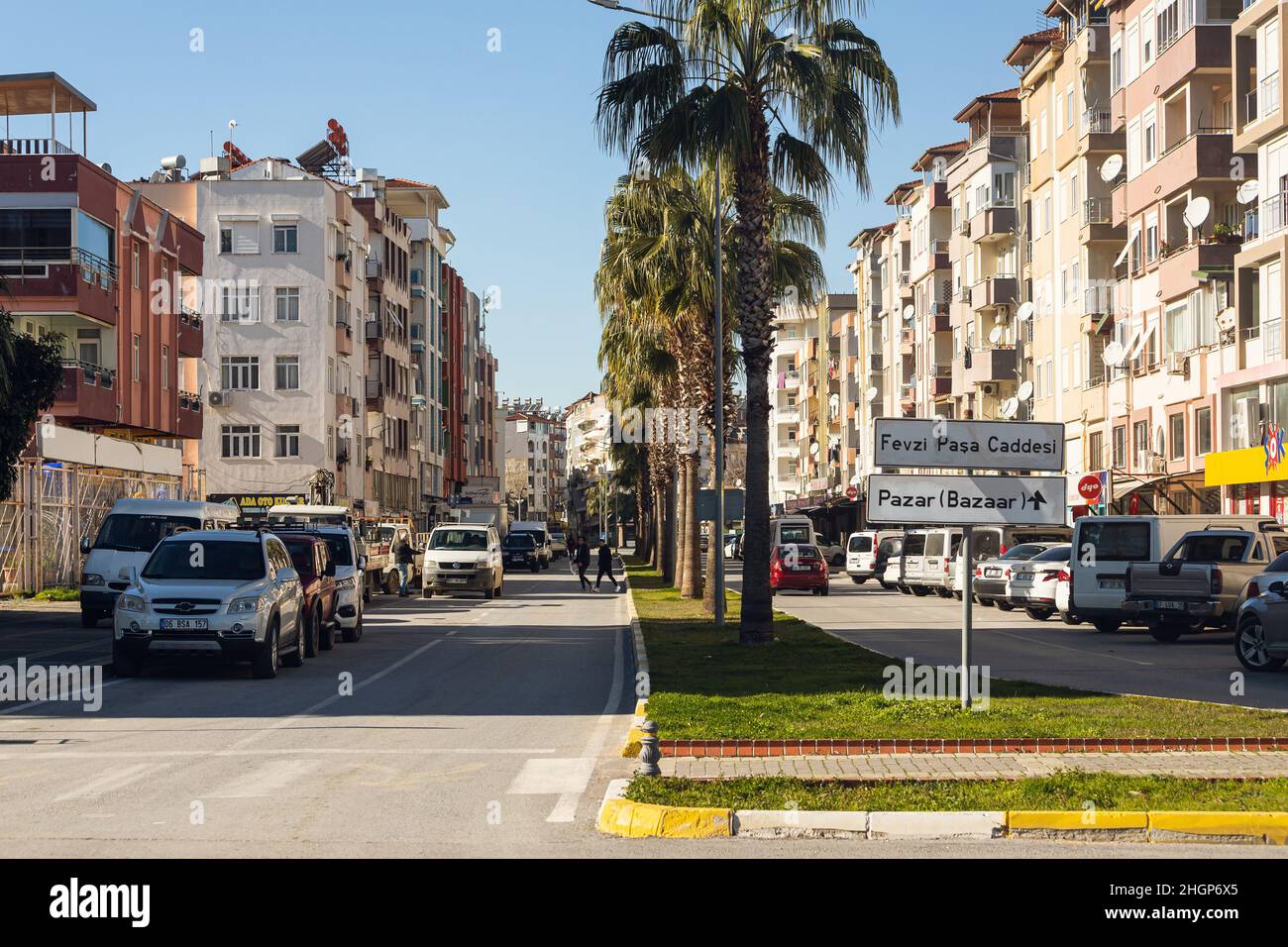 Manavgat, Turchia -20 gennaio 2022: Strada della città con diverse case basse, traffico auto attivo, negozi Foto Stock