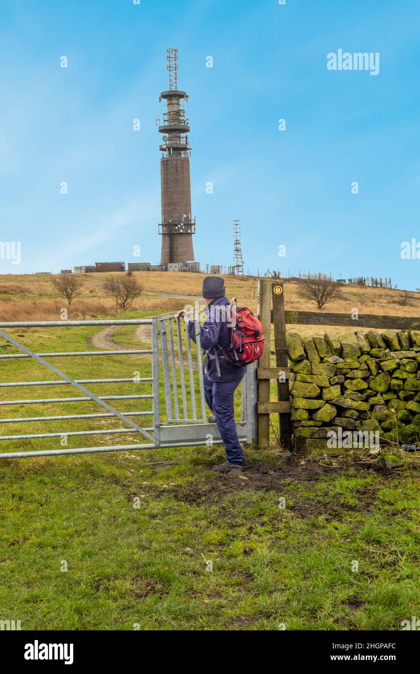 Uomo che cammina lungo il sentiero di pietra verso la torre di telecomunicazioni BT palo radio su Croker Hill Sutton comune vicino Macclesfield Cheshire Foto Stock
