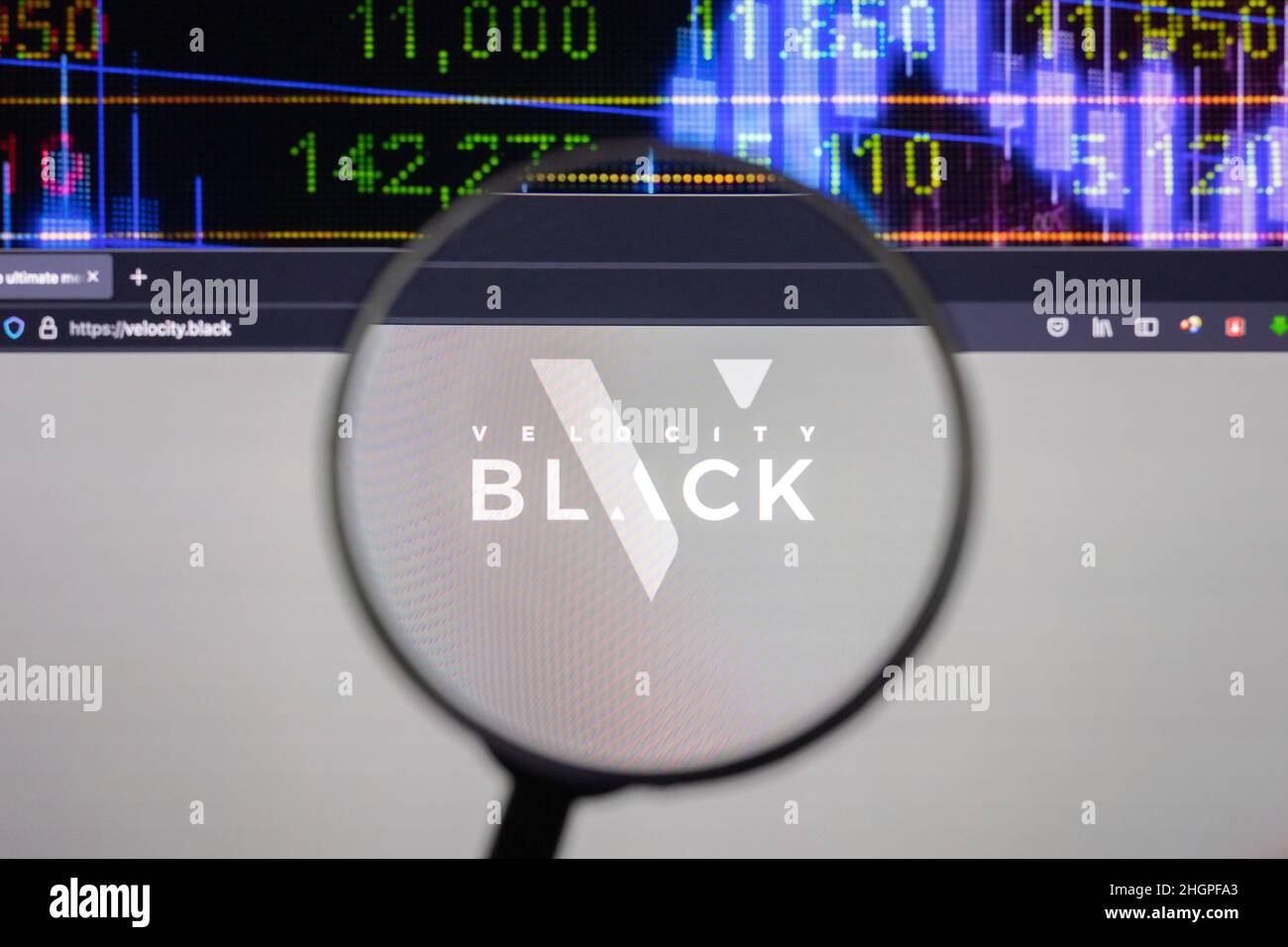 Velocity Black Company logo su un sito web con blurry di mercato azionario sviluppi in background, visto su uno schermo di computer attraverso una lente d'ingrandimento Foto Stock