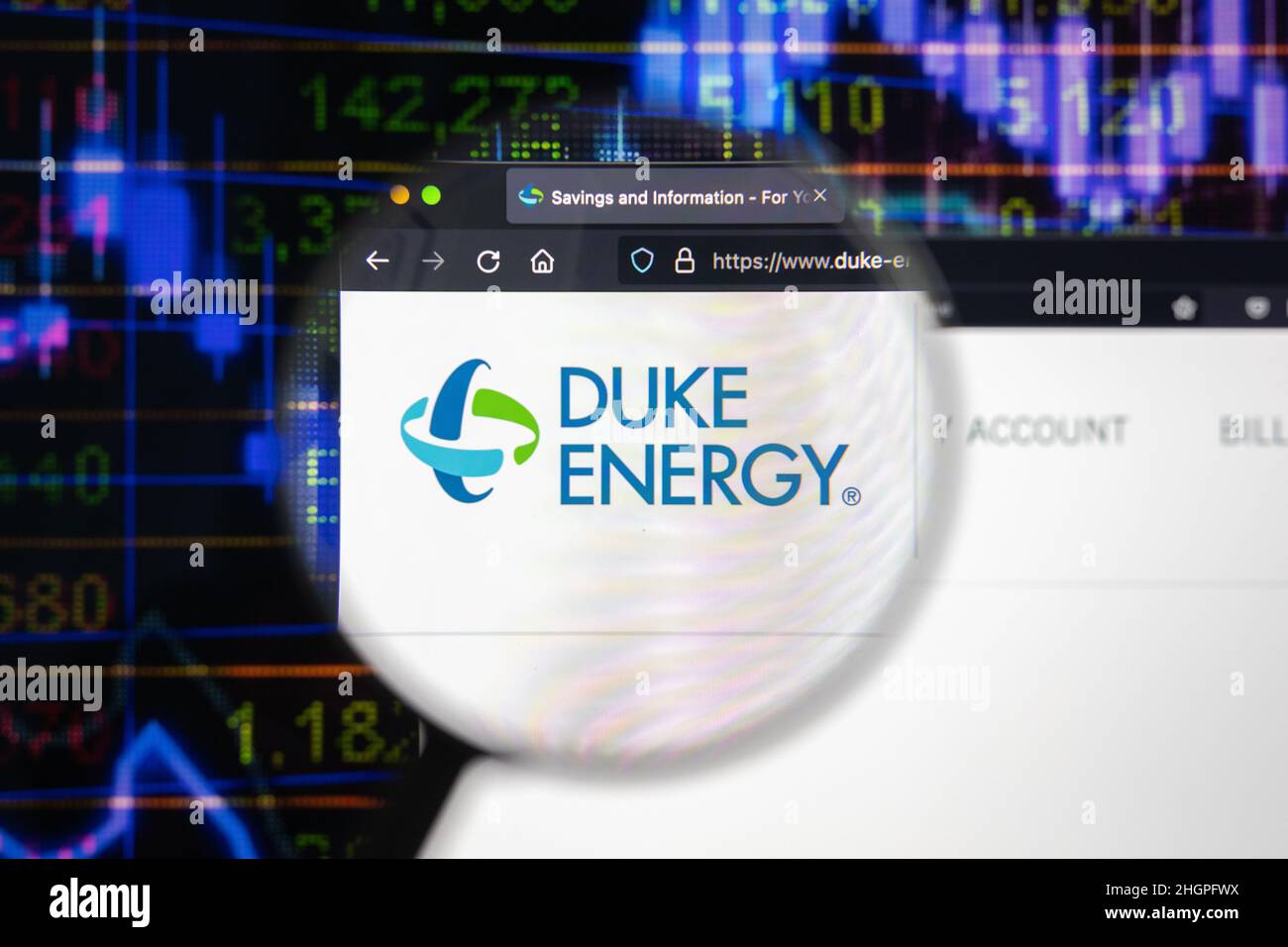 Duke Energy Company logo su un sito web con blurry di mercato azionario sviluppi in background, visto su uno schermo di computer attraverso una lente d'ingrandimento. Foto Stock
