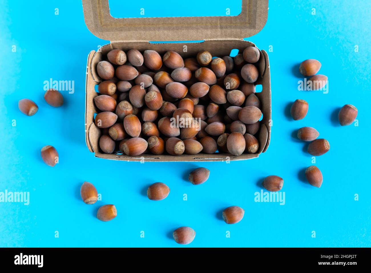 Scatola con nocciole su tavola di pietra, uno sfondo blu piatto Foto Stock