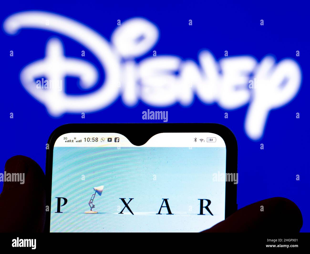 In questa illustrazione, il logo Pixar Animation Studios viene visualizzato sullo schermo di uno smartphone con il logo Disney sullo sfondo. Foto Stock
