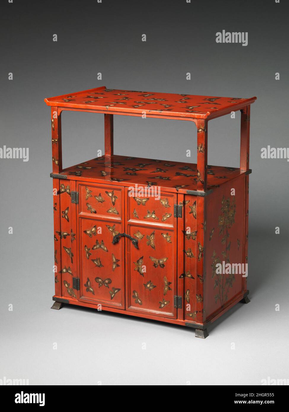 Cabinet con progettazione di farfalle 18th secolo Giappone (Ry?ky? Isole) Farfalle e fiori si trovano spesso nelle arti visive della Cina e del Ry?ky? Isole nel XVIII secolo. Le farfalle che decorano questo mobile sono state dipinte in lacca nera e oro e intarsiate con guscio di perla. La forma complessiva del gabinetto e i quattro piedi piccoli mostrano paralleli all'arte giapponese. Una grande apertura a forma di swastika nella parete posteriore del gabinetto suggerisce che una volta era usata per ospitare sutra buddisti o paraphernalia religiosa. Armadio con progettazione di farfalle. Giappone (Ry?ky? Isole). Foto Stock