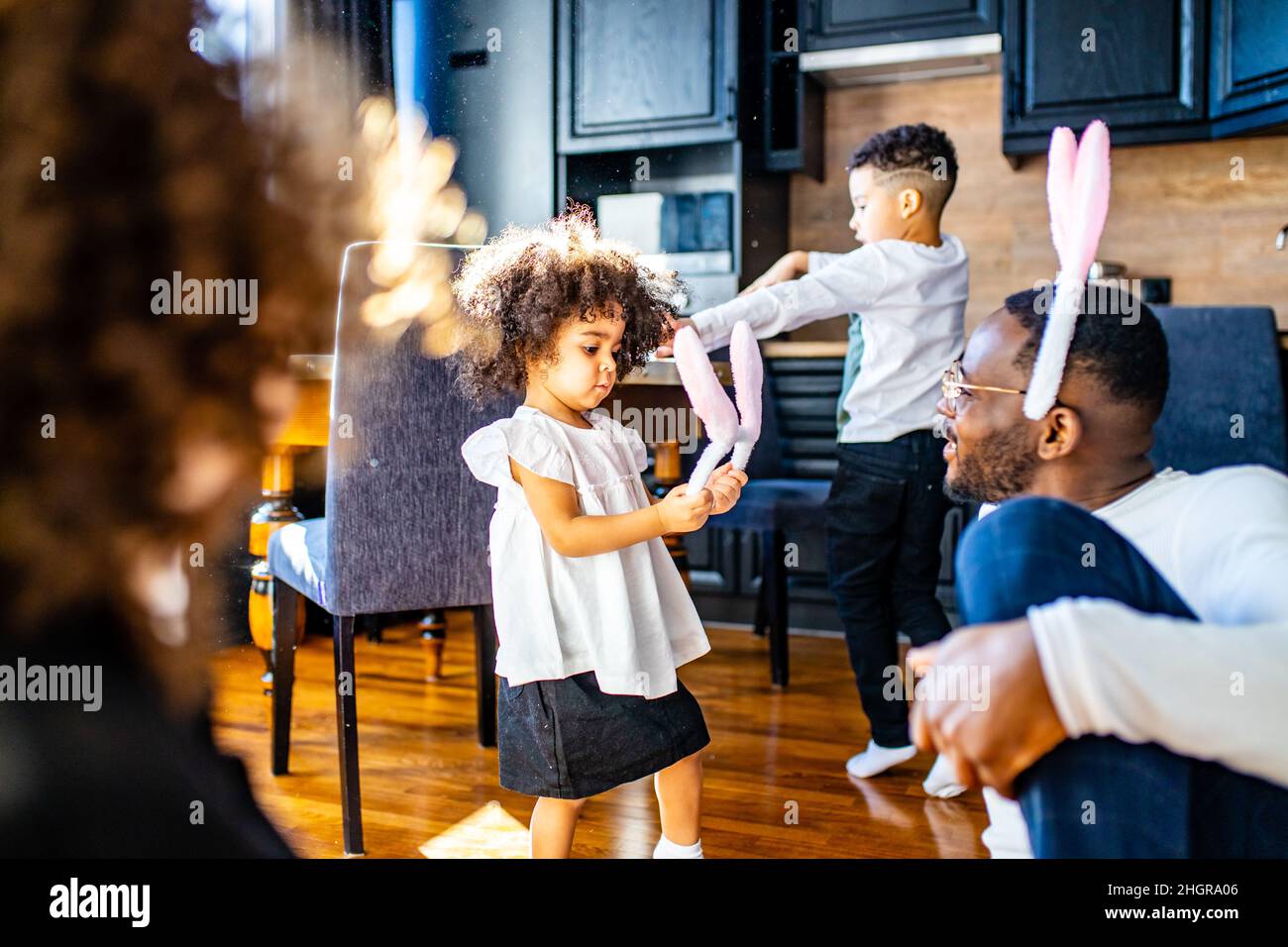 famiglia ispanica multiculturale che indossa le orecchie di coniglio in soggiorno luce soft sole giorno Foto Stock