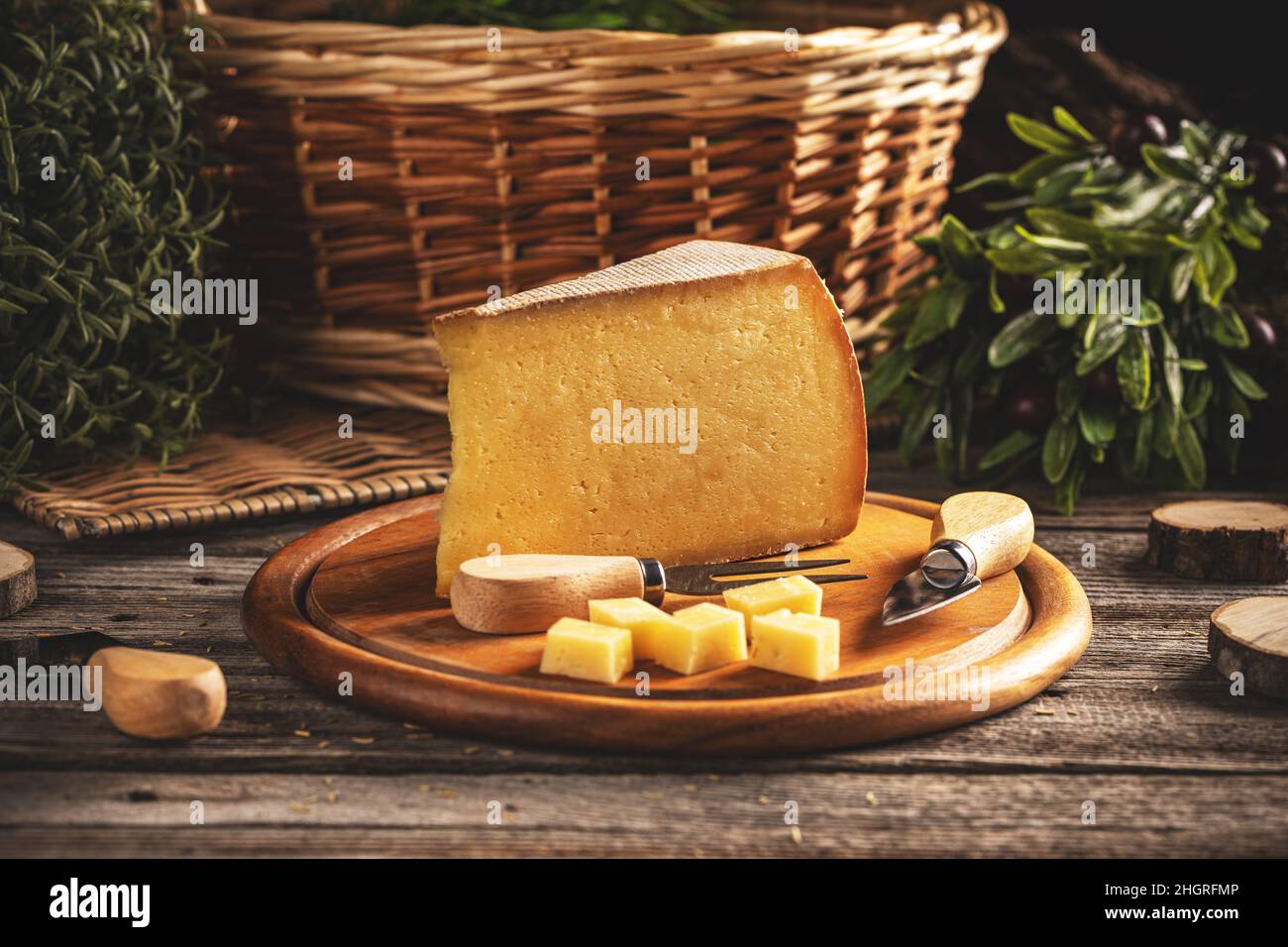 Affettare e cubetti di formaggio giallo a maturazione lunga su tagliere di legno Foto Stock