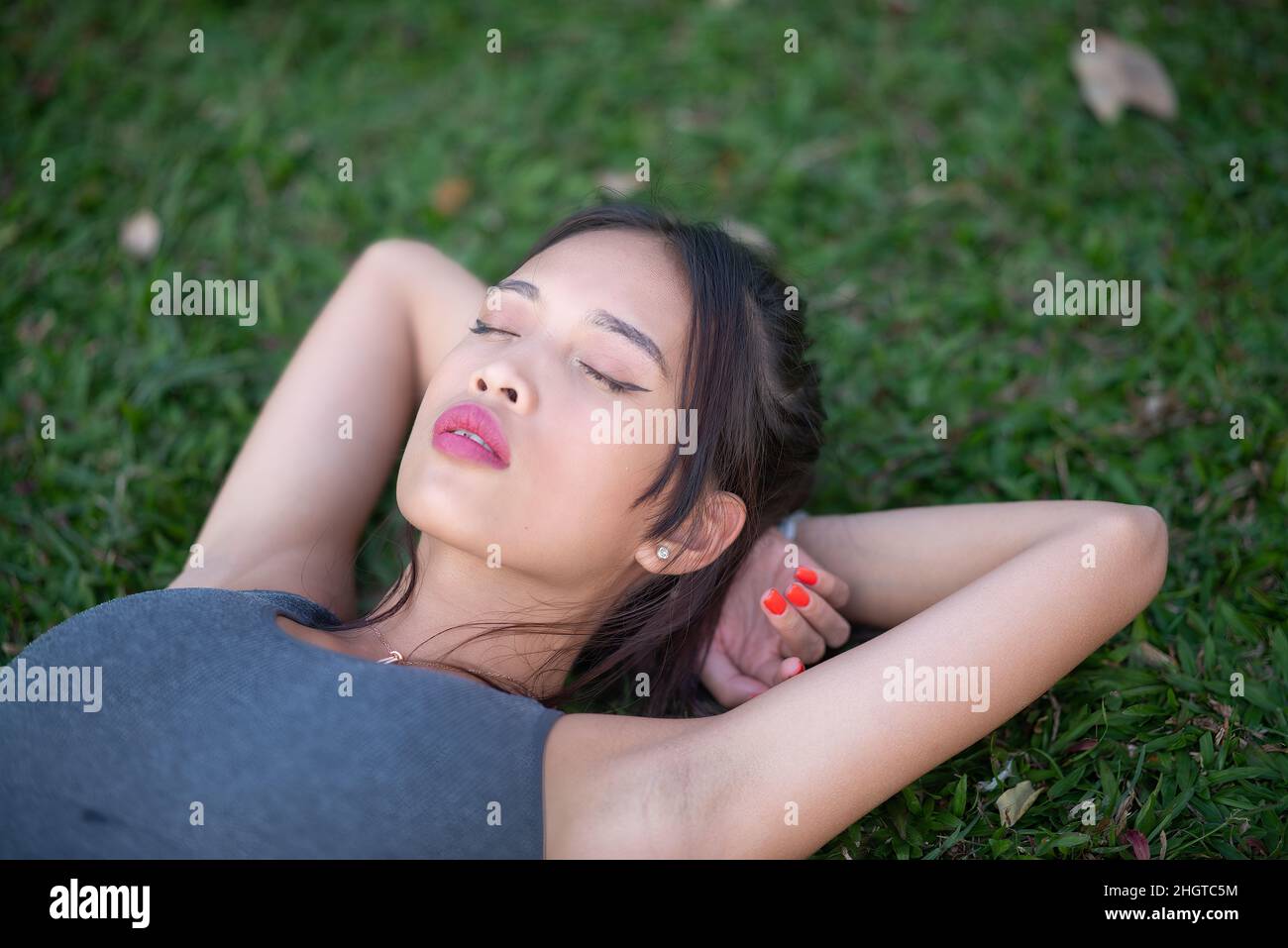 Giovane e bella donna asiatica nel parco della città rilassante dopo allenamento quotidiano Foto Stock