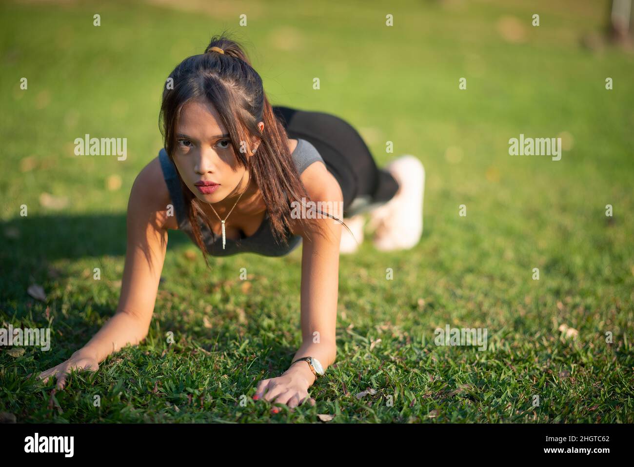 Giovane e bella donna asiatica che si esercita nel parco della città. Concetto di allenamento relax e fitness Foto Stock