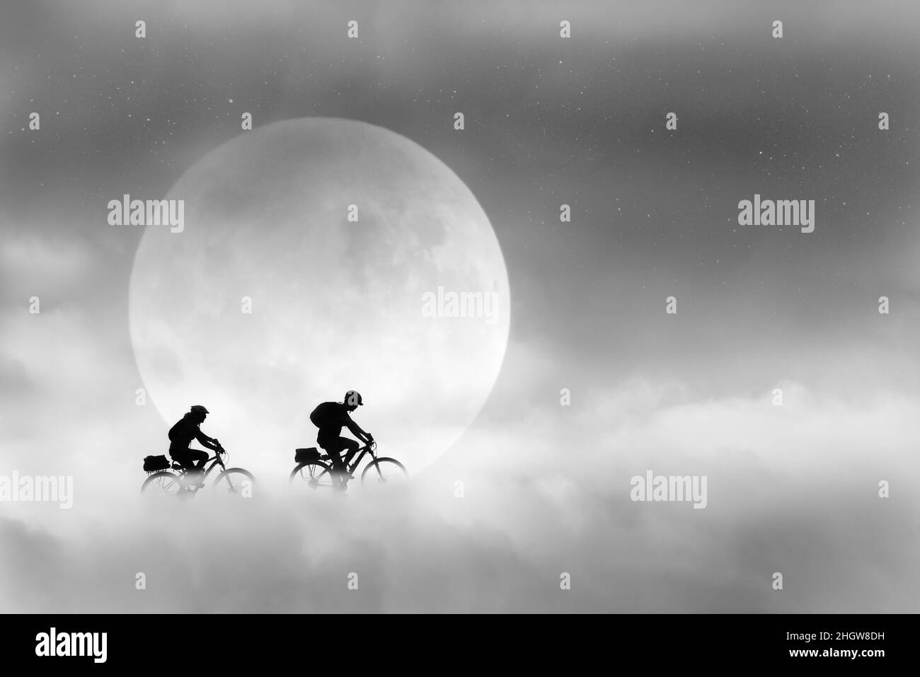 Immagine composita di due giovani in bicicletta tra le nuvole che passano la luna piena con stelle nel cielo. Un'immagine fantasy in bianco e nero. Foto Stock