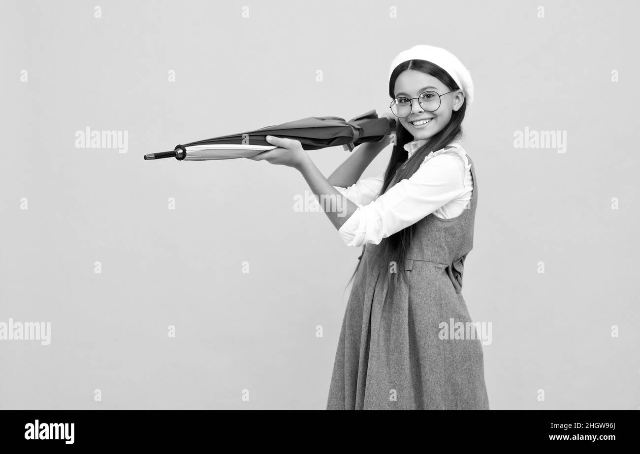 felice ragazza teen in occhiali e beret tenere ombrello colorato per la protezione contro la pioggia, previsioni meteo. Foto Stock