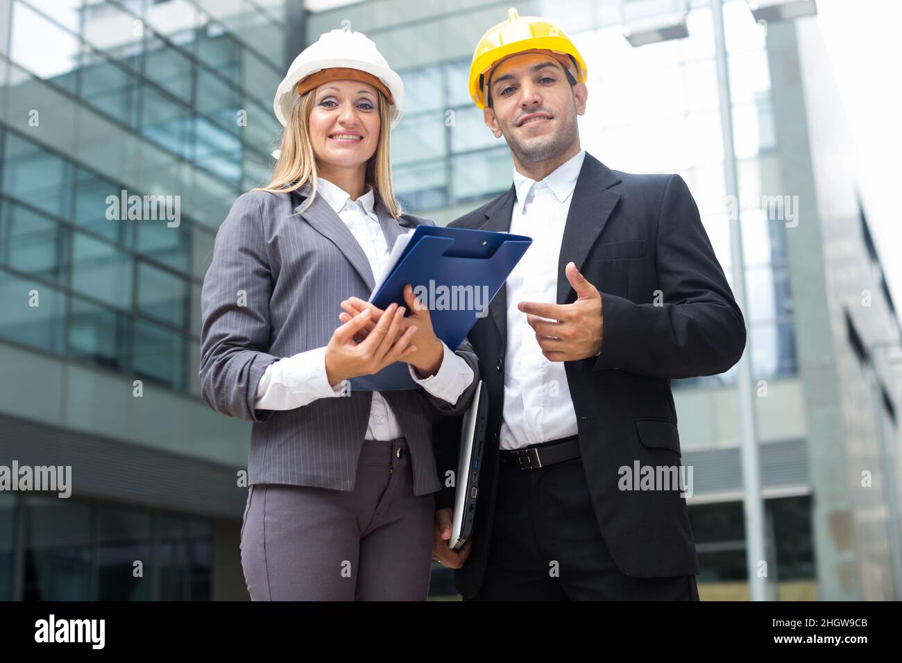 La designer femminile e il suo partner sono in piedi con i documenti Foto Stock