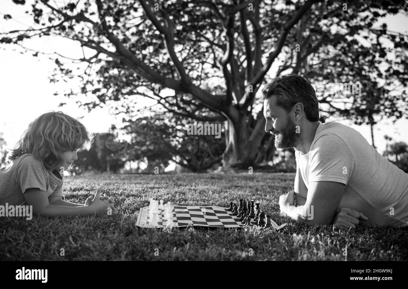 padre e figlio che giocano a scacchi sull'erba nel parco. giorno dei padri. famiglia felice. genitorialità e infanzia. Foto Stock