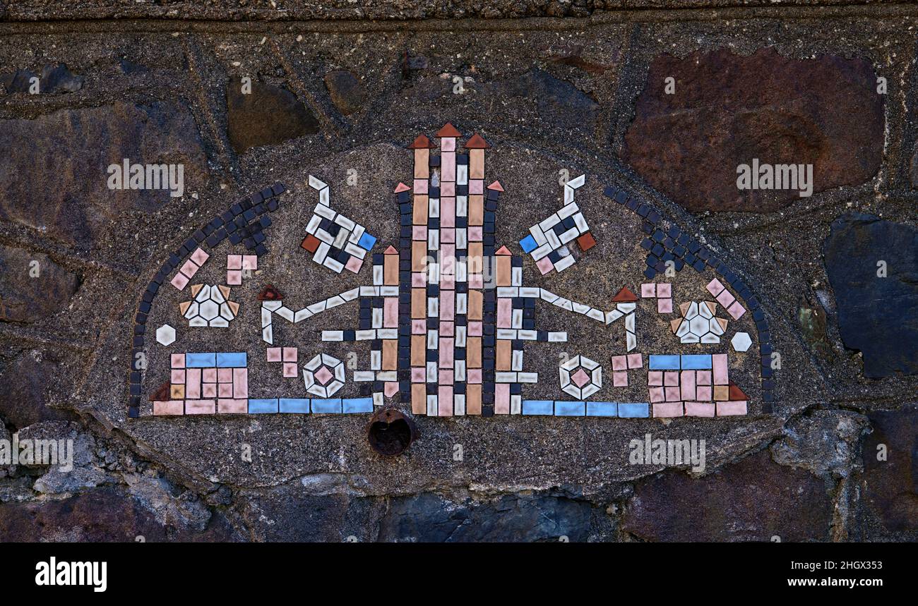 Un bellissimo mosaico rosa, blu, bianco e nero. Le piastrelle sono su un muro di pietra e molto vecchie. Foto Stock