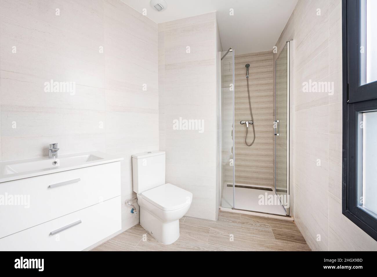 Bagno in toni chiari con pensile bianco e doccia con schermo in vetro Foto  stock - Alamy