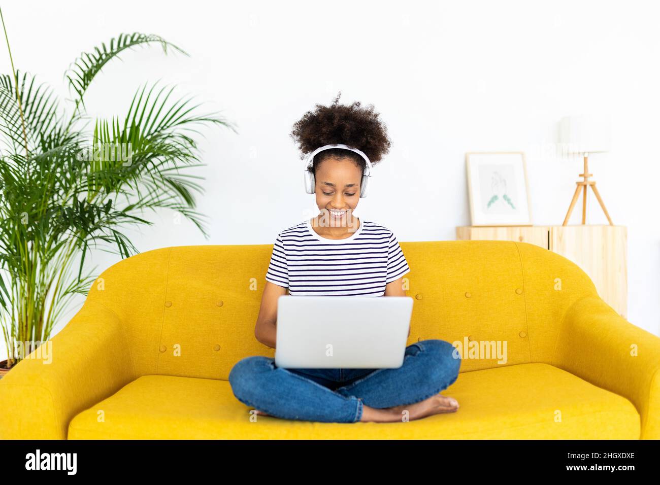 Ragazza afroamericana che lavora sul laptop mentre si siede sul divano a casa Foto Stock