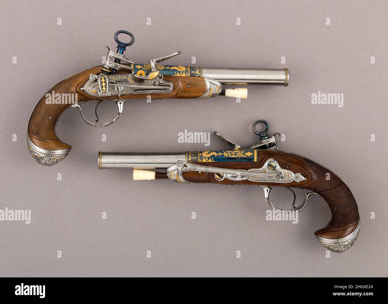 Coppia di pistole con Flintlocks a Las Tres Modas fine 18th secolo laboratorio della famiglia Ybarzabel spagnolo canne di pistola spagnolo sono stati rinomati per la loro qualità dal XVI secolo. Una produzione significativa di armi da fuoco non si sviluppò, tuttavia, fino al secolo successivo e l'invenzione di un meccanismo originale di flintlock soprannominato miquelet (una parola francese che significa 'bandito panish'). A causa del vasto commercio spagnolo e dei vasti possedimenti territoriali, le armi da fuoco spagnole con questo dispositivo di accensione sono diventate popolari in tutte le regioni mediterranee e in Medio Oriente. Il miquelet era così robusto e affidabile t Foto Stock
