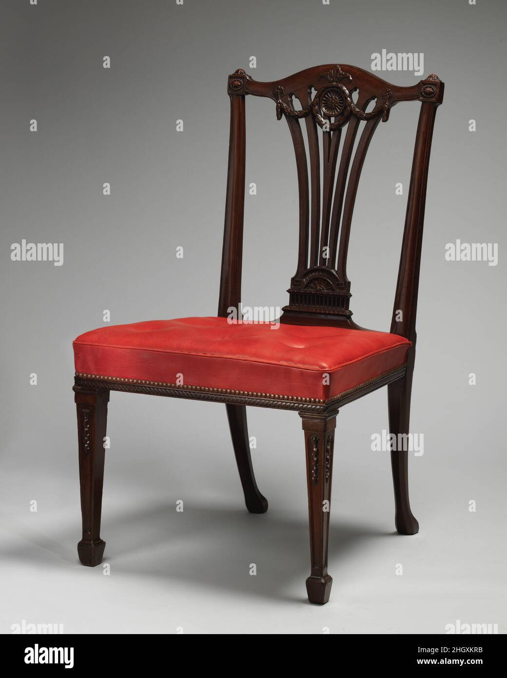 Sedia laterale (una di un set di quattordici) ca. 1772 Robert Adam Chippendale eseguì questo set di sedie da pranzo in mogano neoclassico per Goldsborough Hall, nello Yorkshire, che apparteneva a Daniel Lascelles, fratello minore del patrono più stravagante di Chippendale, Edwin Lascelles, della vicina Harewood House. Il set, che originariamente includeva quindici sedie, rimase a Goldsborough fino al 1929, quando fu rimosso a Harewood House, da dove fu venduto nel 1976. Le sedie rappresentano uno dei disegni più eleganti di Chippendale: I loro schienali rastremati hanno binari superiori ad arco e lati stampati con testa a perla Foto Stock