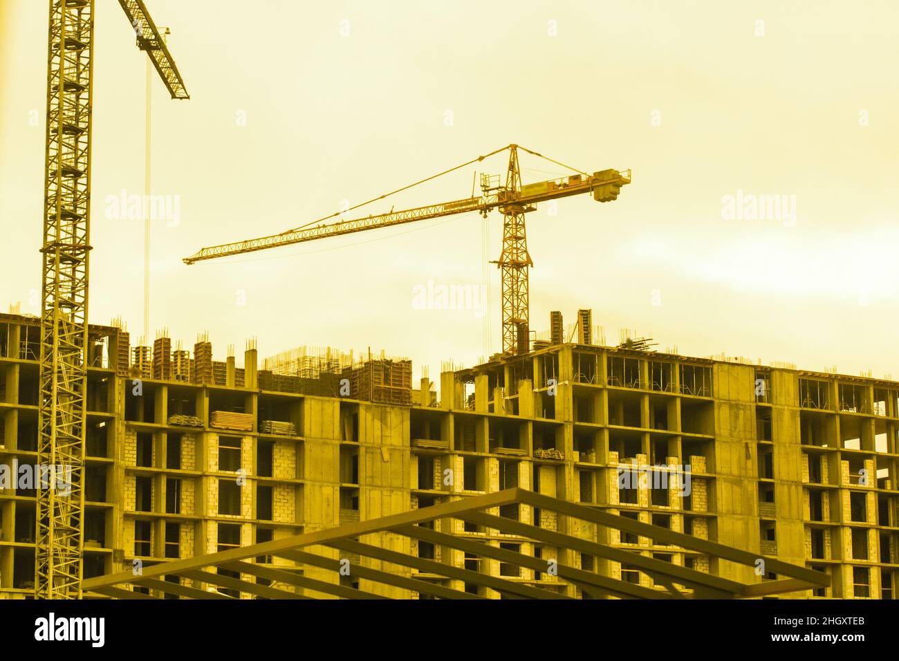 Costruzione gru da cantiere industriale sullo sfondo di un cielo giallo soleggiato e lo sviluppo del tramonto. Foto Stock