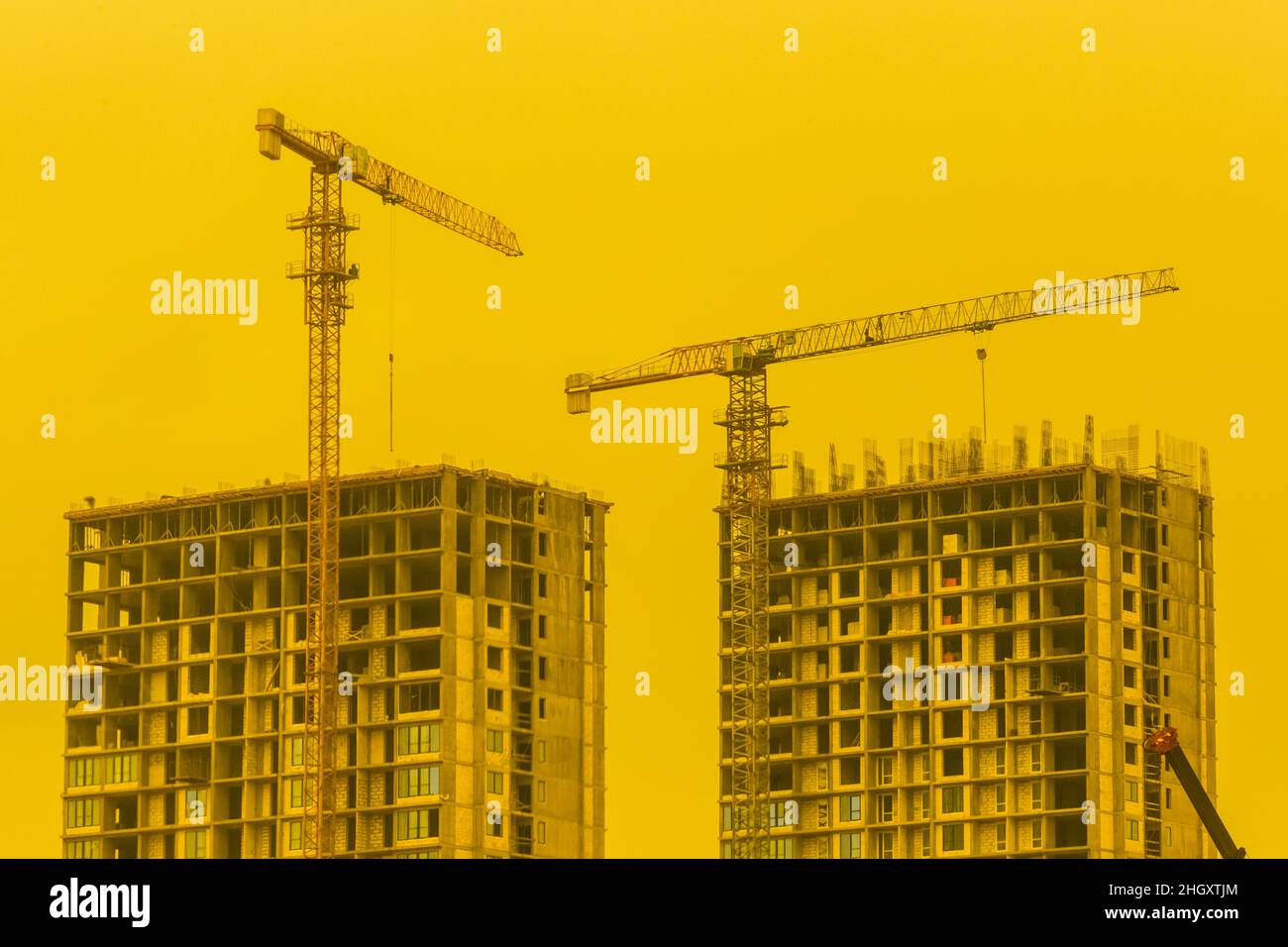 Costruzione gru da cantiere industriale sullo sfondo di un cielo giallo soleggiato e lo sviluppo del tramonto. Foto Stock