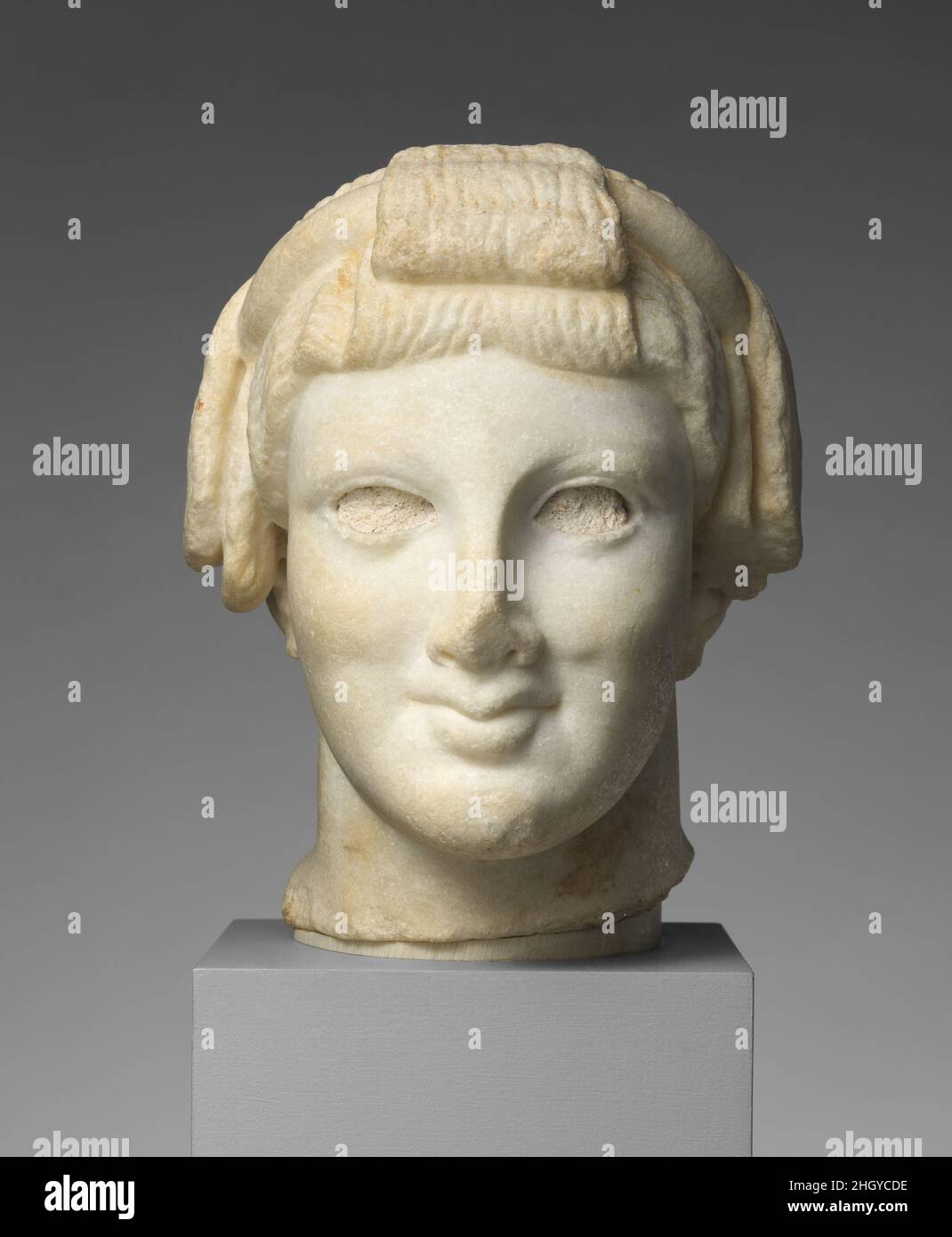 Testa di marmo di Apollo ca. 27 A.C.-D.C. 68 Roman la disposizione dei capelli a cappi evoca quella del giovane dio Apollo come era rappresentato in statue datanti alla fine del 6th e all'inizio del 5th secoli a.C. le figure di arcaising erano popolari nel periodo romano, e questa testa, probabilmente posta su un albero rettangolare di erma, sarebbe stato un ornamento giardino adatto. Testa di marmo di Apollo. Romana. CA. 27 A.C.-D.C. 68. Marmo. Augusta o Julio-Claudian. Scultura di pietra Foto Stock