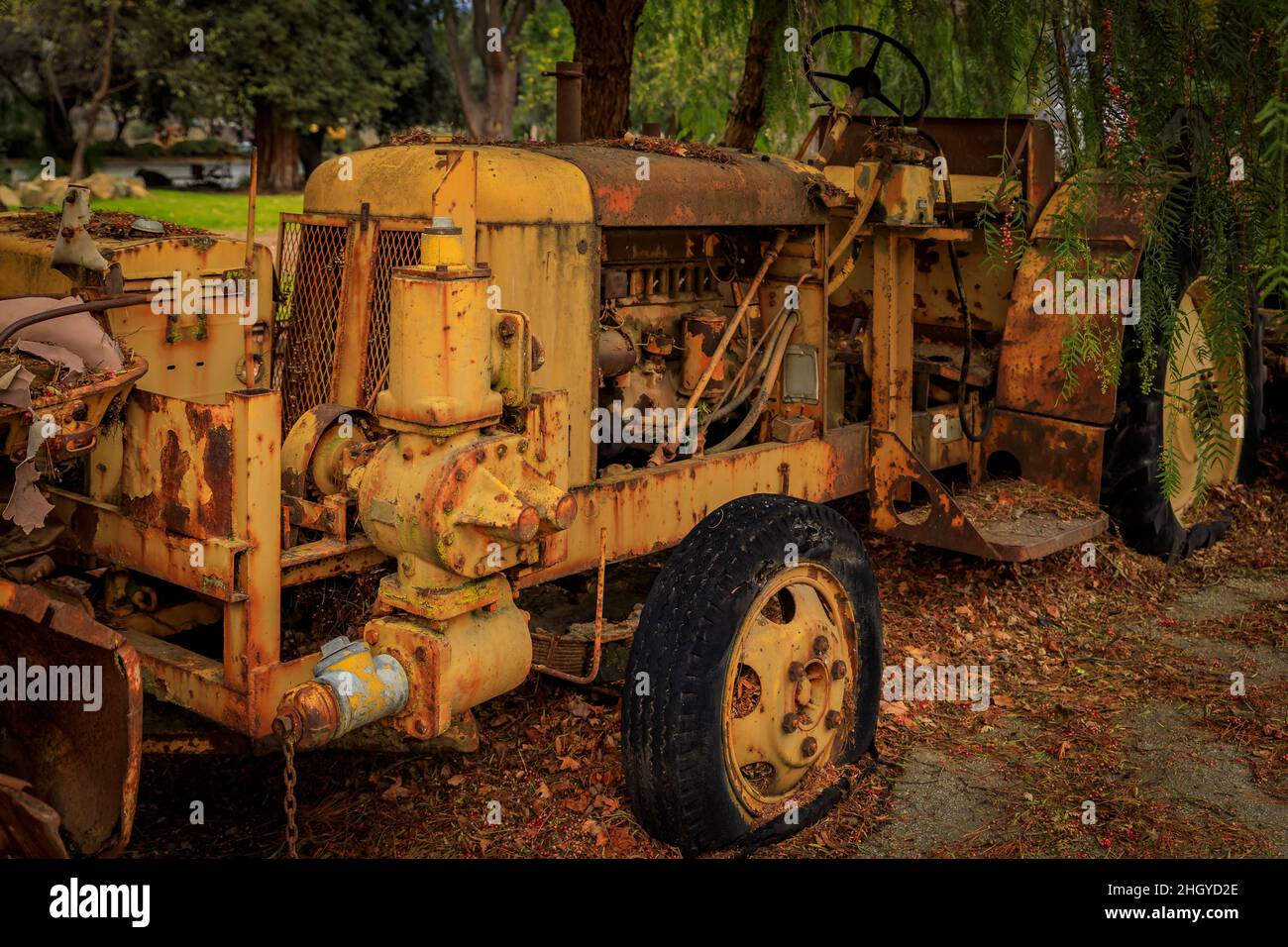 Vecchie e arrugginite abbandonarono attrezzature pesanti, trattori, escavatori e bulldozer tra alberi con foglie gialle cadute sul terreno Foto Stock