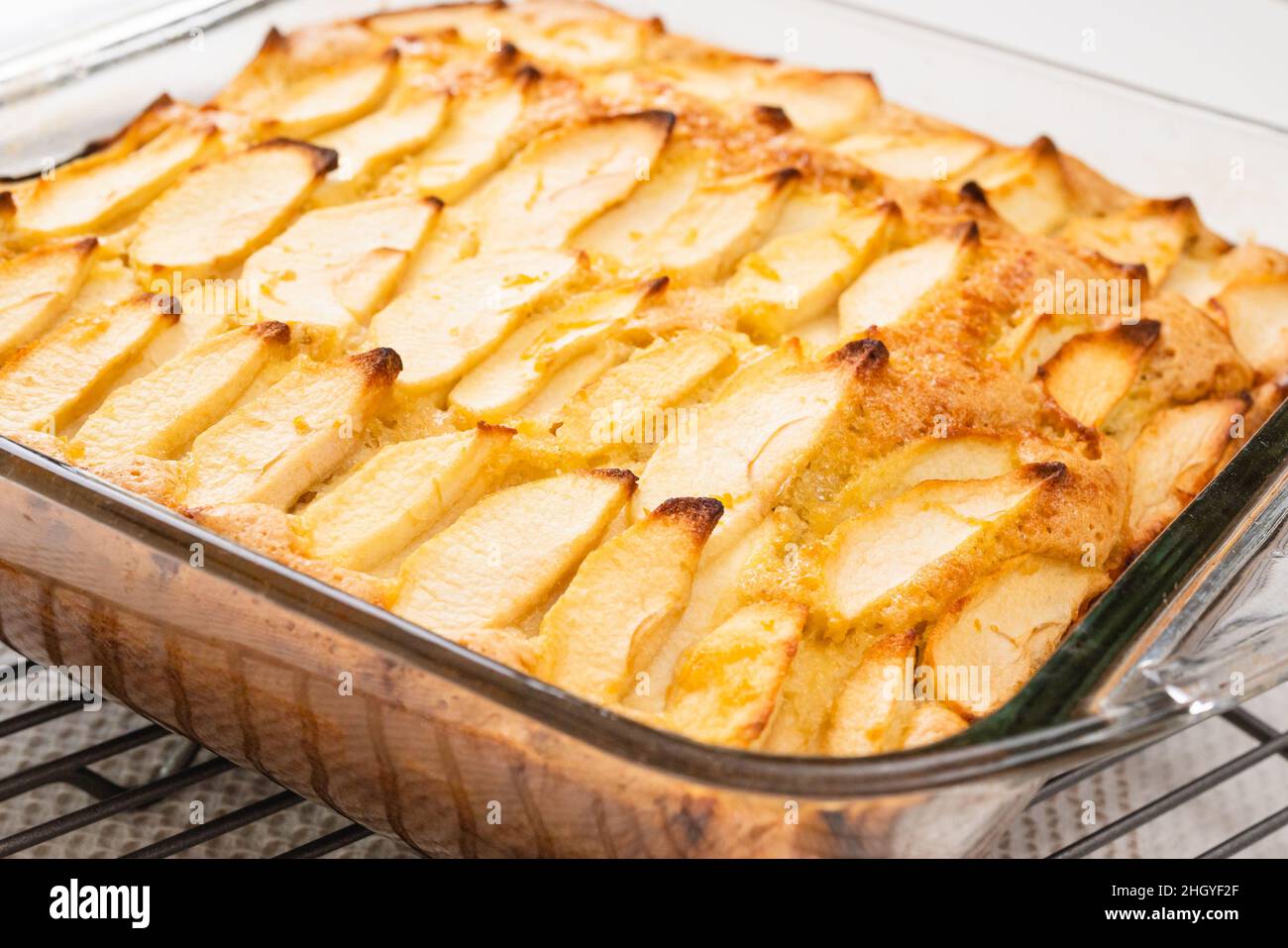 Torta di mele appena sfornata con base di biscotti da vicino in una teglia da forno in vetro sul tavolo da cucina, appena dal forno Foto Stock
