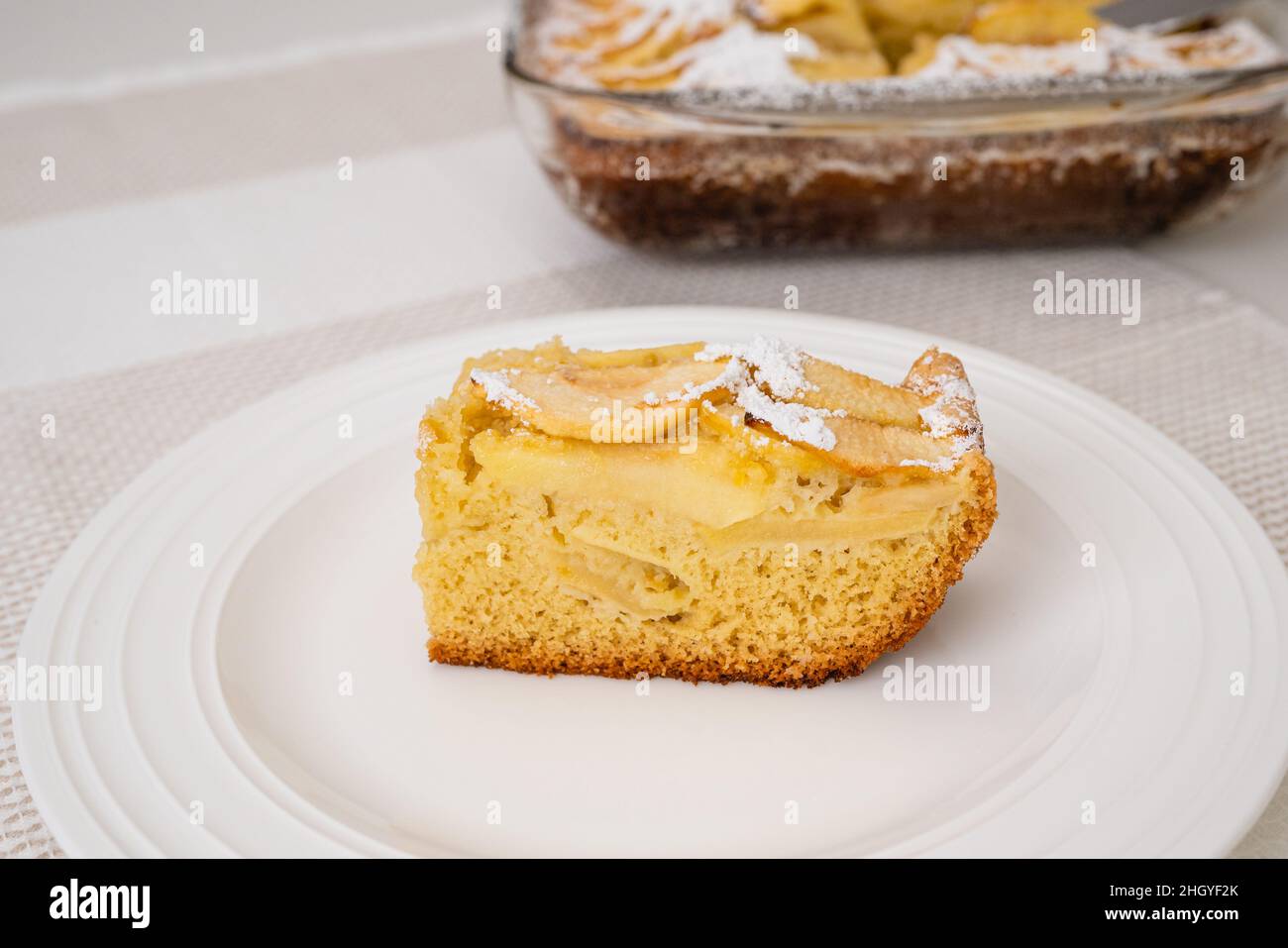 Fetta di torta di mele con base di biscotti da vicino su un piatto bianco. Dolce di mele fatto in casa appena sfornato Foto Stock