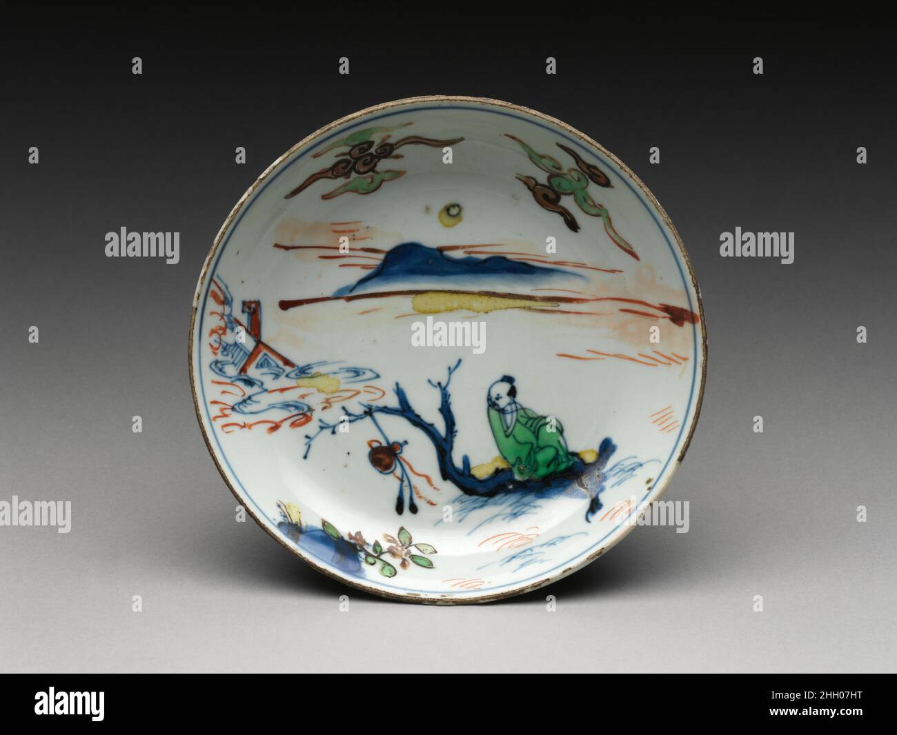 Piatto con un immortale su zattera Cina la scena su questo piatto rappresenta il diplomatico e speditore Zhang Qian (164–113 a.C.), che ha guidato l'inviato imperiale Han nelle regioni occidentali. La leggenda vuole che quando Zhang tentò di trovare la sorgente del Fiume giallo salpò la sua zattera nella Via Lattea. La figura qui si siede con sicurezza su un singolo ceppo in una postura distesa fra le onde turbolente. Piatto con un immortale su zattera. Cina. Porcellana dipinta in smalto policromo e smalto (Jingdezhen ware). Dinastia Ming (1368-1644), marchio Tianqi e periodo (1621-27). Ceramica Foto Stock