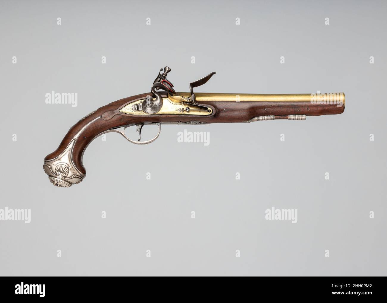 Pistola flintlock ca. 1771–72 probabilmente John Hall questa pistola presenta una piastra laterale in rococo d'argento e un pommel d'argento adornato con una maschera-decorazioni tipiche di molte armi da fuoco inglesi di inizio a metà del 18th secolo. Pistole dotate di botti di ottone e serrature come questa, meno costose di quelle realizzate con componenti in acciaio, sono state ampiamente prodotte nei centri di produzione di armi da fuoco di Londra e Birmingham. Pistola flintlock. Inglese, Londra. CA. 1771–72. Acciaio, legno (noce), ottone, argento. Londra. Armi da fuoco-Pistoli-Flintlock Foto Stock