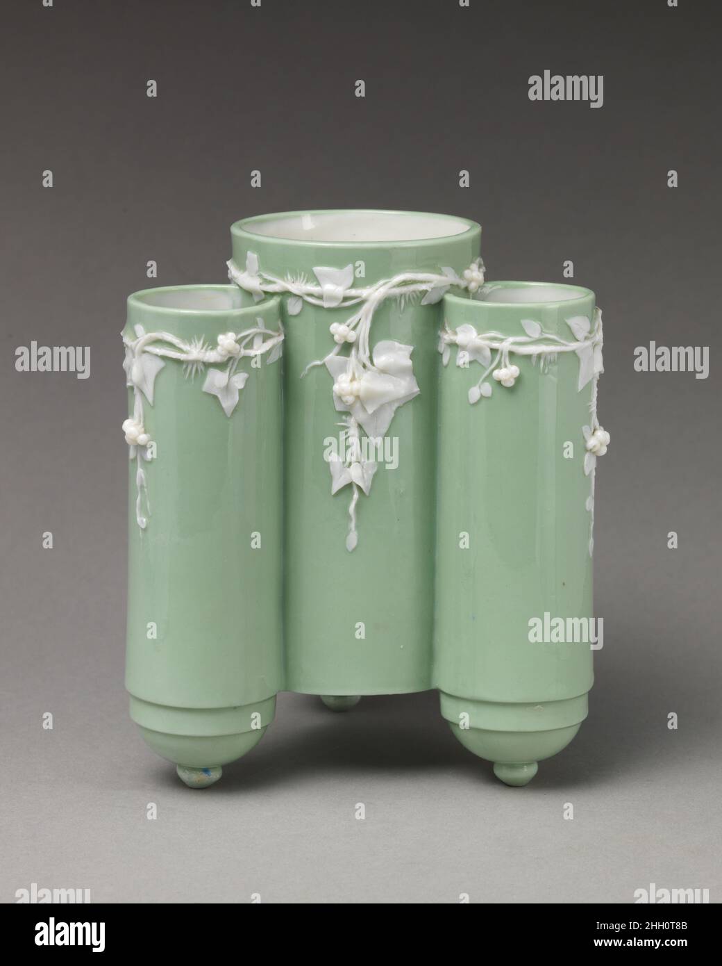 Vaso a corpo cilindrico triplo con motivo d'edera 1870 Minton(s) Minton è stata la più importante fabbrica di ceramica durante il periodo vittoriano e ha iniziato ad esporre i prodotti alla prima Grande esposizione del 1851. Fondata nel 1793 da Thomas Minton a Stoke-on-Trent, la società si specializzò inizialmente in ceramica transferware prima di espandersi sotto la proprietà del figlio di Thomas, Herbert Minton, a partire dal 1836. Sotto la proprietà di Colin Minton Campbell, che successe a suo zio nel 1858, la fabbrica divenne riconosciuta come un produttore specializzato di porcellana movimento estetico, che furono ispirate da una ricca arra Foto Stock