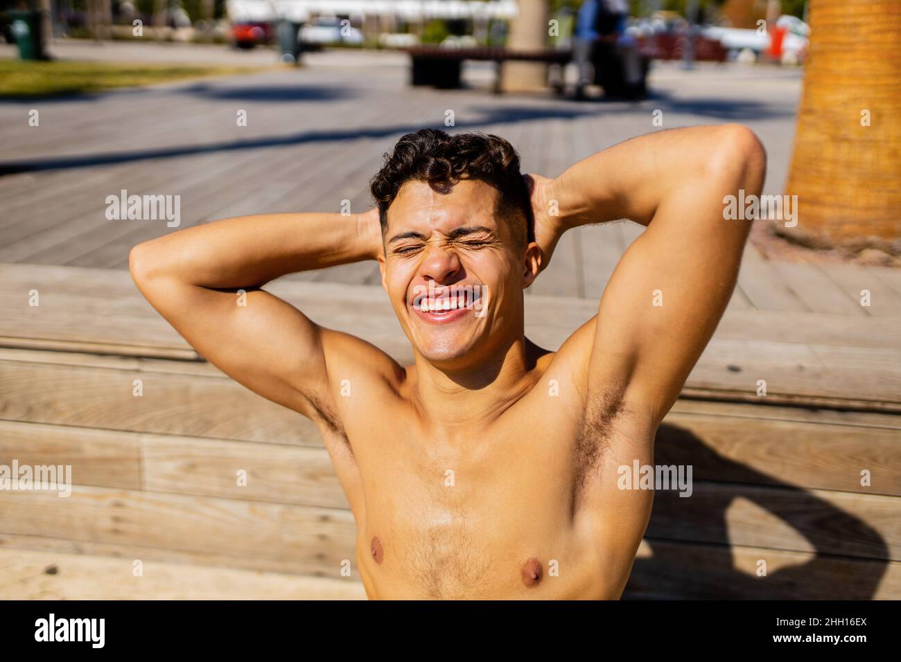 uomo latino che applica lozione di abbronzatura al mare con sfondo di palme Foto Stock