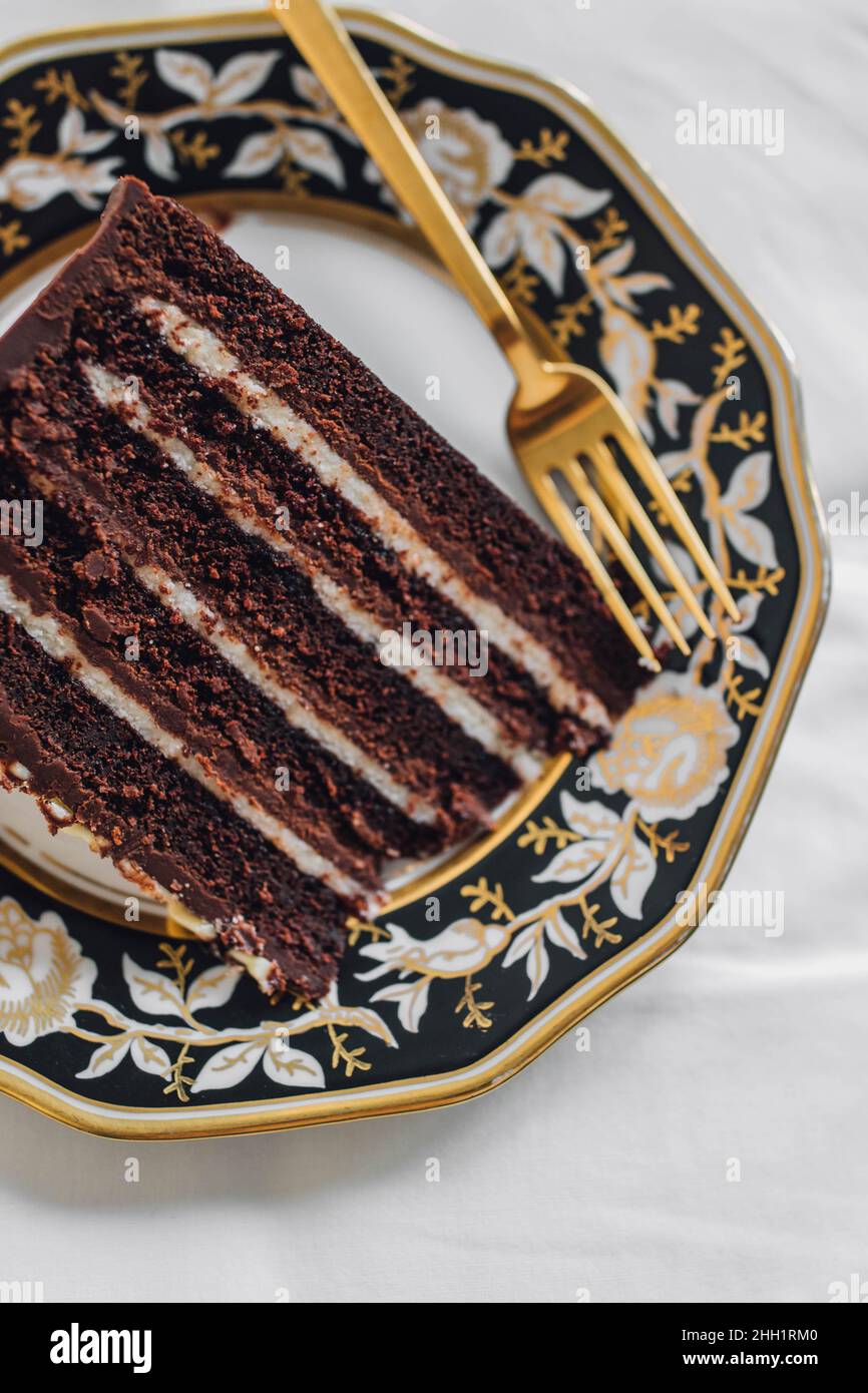 Torta al cioccolato Diavolo's Food su un piatto d'oro bianco nero con forchetta d'oro Foto Stock