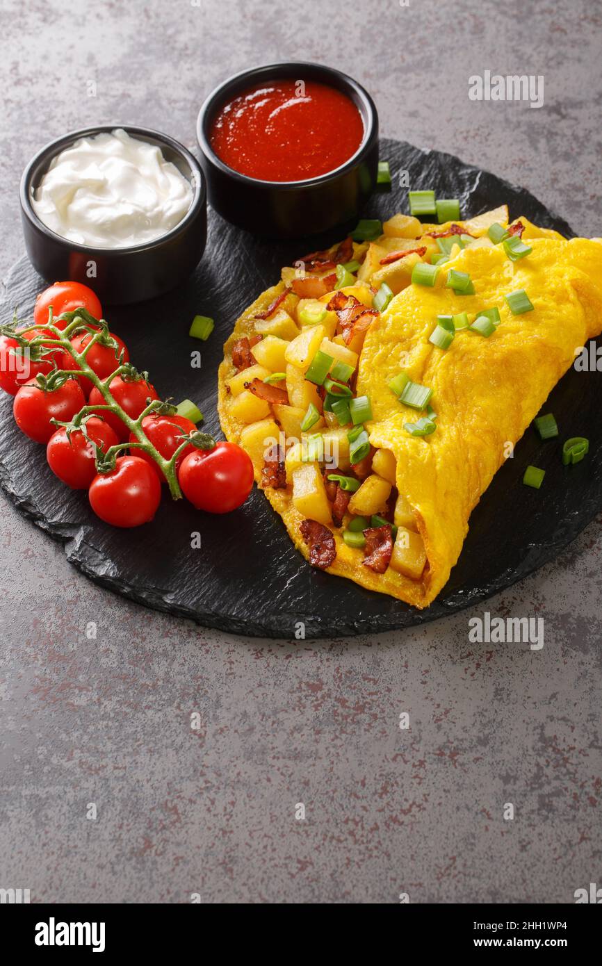 Prima colazione tedesca Bauernomlett agricoltori Omelet con patate fritte primo piano su una tavola di ardesia sul tavolo. Verticale Foto Stock