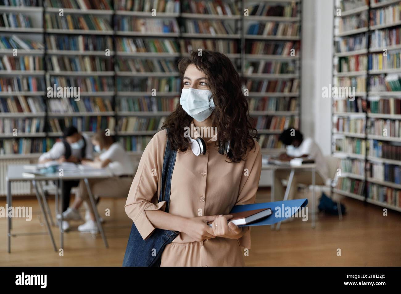 Sorridente ispanica femmina studente in maschera medica protettiva visita pubblico Foto Stock