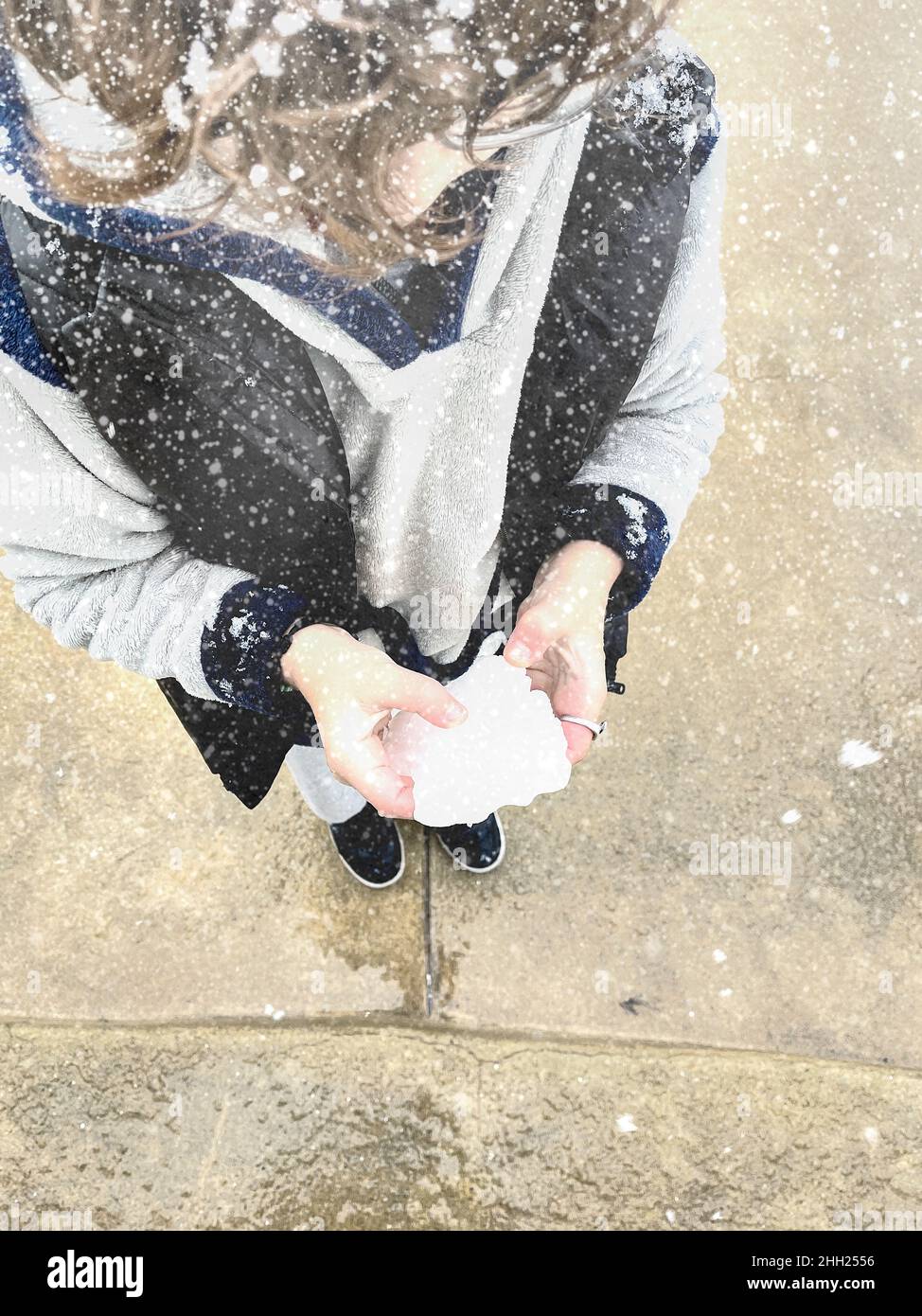 Giovane ragazzo che si gode la prima nevicata e che tiene una palla di neve nelle sue mani. Immagine stock. Foto Stock