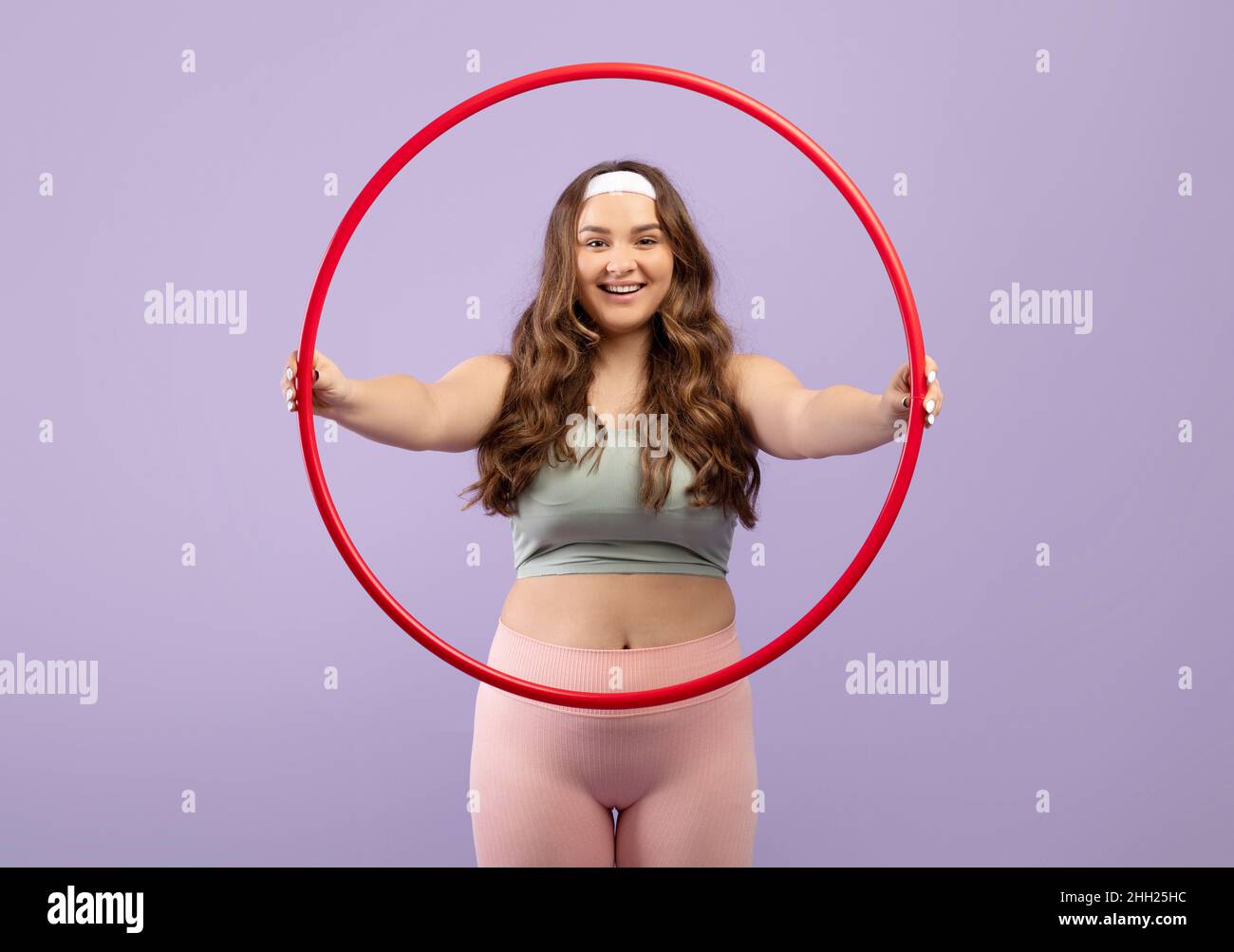 Felice caucasico felice più taglia giovane donna in uniforme sport tenere hula hoop Foto Stock