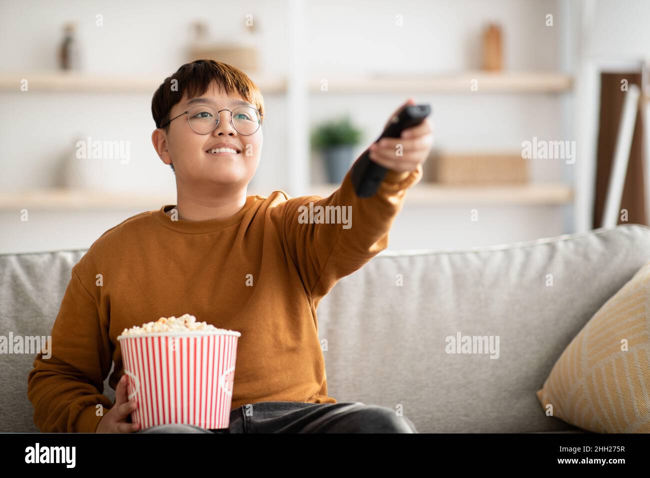 Gioioso bambino asiatico guardando la TV a casa Foto Stock