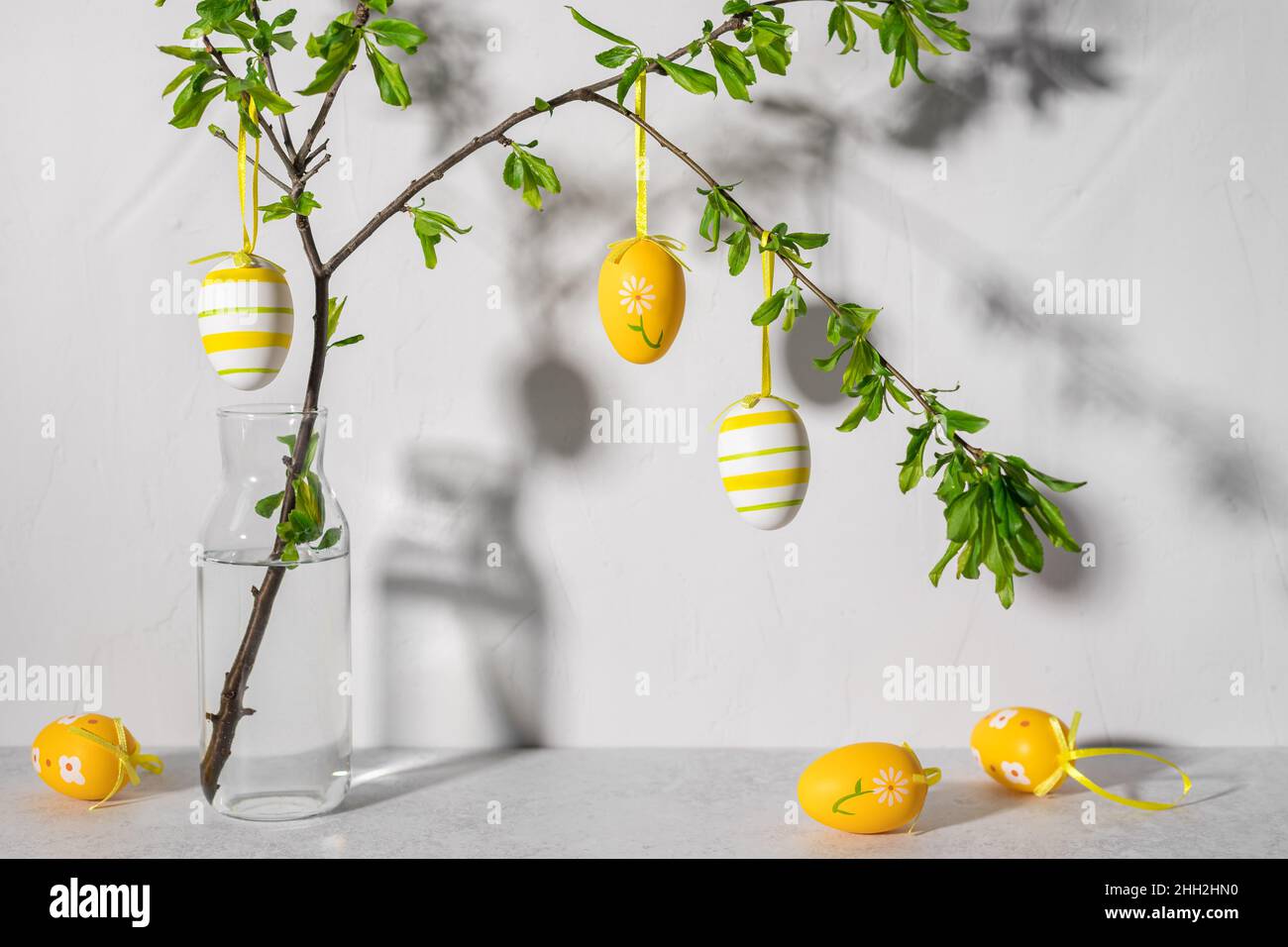 Albero di Pasqua con uova di Pasqua colorate contro il muro grigio Foto Stock