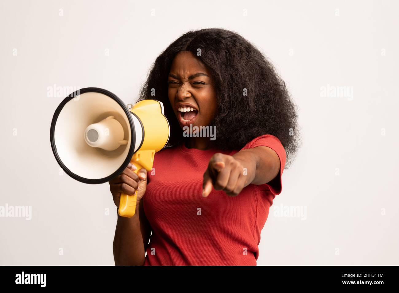 Aggressiva African American Woman gridando con Megaphone e puntando la mano alla macchina fotografica Foto Stock