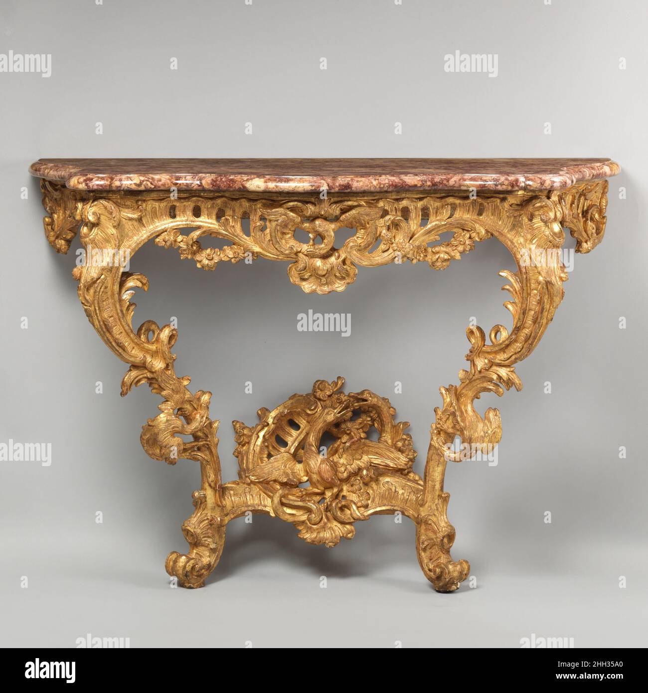 Tavolo console (uno di una coppia) ca. 1735–40 francesi questi tavolini laterali hanno supporti riccamente intagliati, trafitto ovunque con forme asimmetriche di conchiglie e ritocchi, ghirlande floreali, fogliame e uccelli e sono una meravigliosa espressione dello stile rococò. Tali tavole erano opera di falegnami o menuisieri che erano coinvolti principalmente nella preparazione di legname da costruzione. Le sculture decorative sono state completate da fegati altamente qualificati – nessuno degli artigiani ha firmato il loro lavoro e la loro identità rimane sconosciuta. Tavolo della console (uno di una coppia). Francese. CA. 1735–40. Pino: Intagliato e dorato; brocatello m Foto Stock