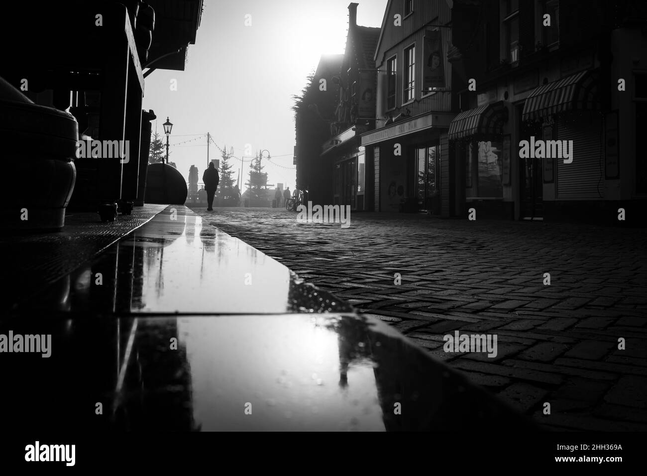 166 / 5,000 Vertaalresultaten Fotografia in bianco e nero di un uomo che cammina da solo sulla strada con il Sole dietro di lui. Foto astratta della vita di strada i Foto Stock