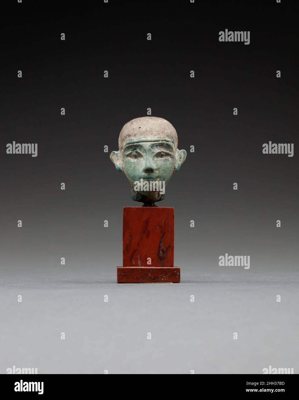 Capo di Ptah ca. 1550–1000 A.C. (?) Nuovo regno o più tardi Dio della città di Memphis, Ptah era associato principalmente con l'arte e l'artigianato. Si presume che egli abbia acquisito la sua designazione di Dio creatore attraverso questa stretta connessione con artigiani, costruttori, e artisti. Piccole figure divine votive in fede, così come in bronzo, sono state depositate come offerte all'interno dei templi egiziani per compiacere gli dei.. Capo di Ptah. Ca. 1550–1000 A.C. (?). Faience. Nuovo Regno o successivo. Dall'Egitto Foto Stock