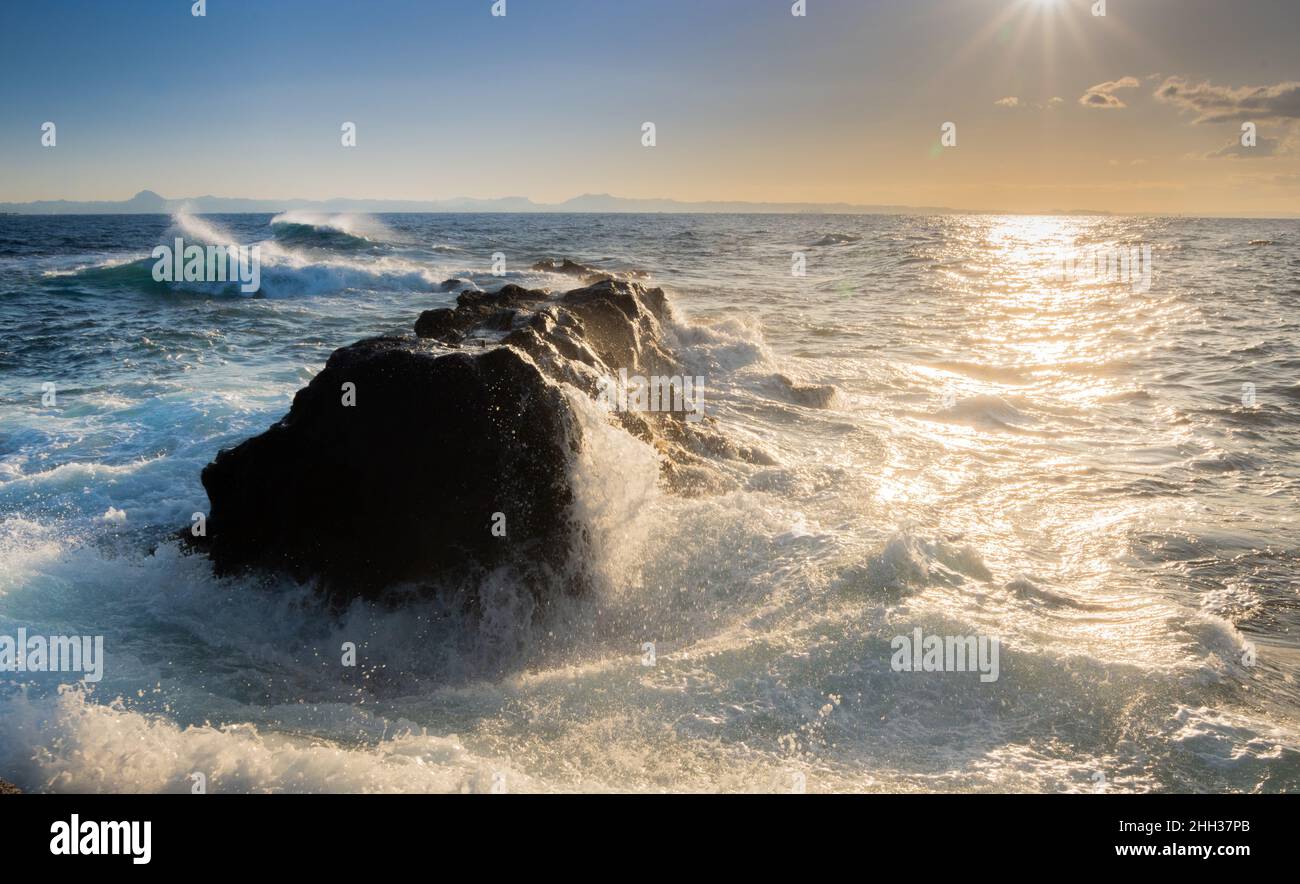Mentre la marea spinge le onde verso la riva, un vento offshore soffia contro le creste delle onde in una battaglia testa a testa di forze naturali. Foto Stock