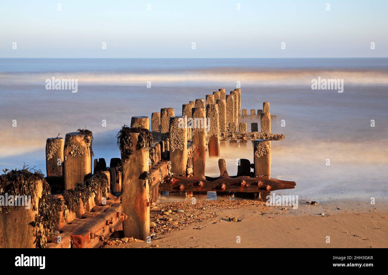 Un fine studio d'arte di un deteriorante frangiflutti in legno che utilizza una lunga esposizione nel Norfolk del Nord a Cart Gap, Happisburgh, Norfolk, Inghilterra, Regno Unito. Foto Stock