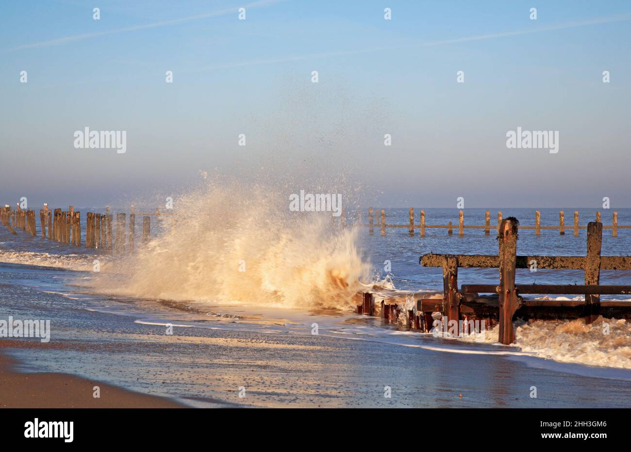 Un'onda che si schiantò contro le erose difese del mare in inverno sulla costa nord del Norfolk a Cart Gap, Happisburgh, Norfolk, Inghilterra, Regno Unito. Foto Stock
