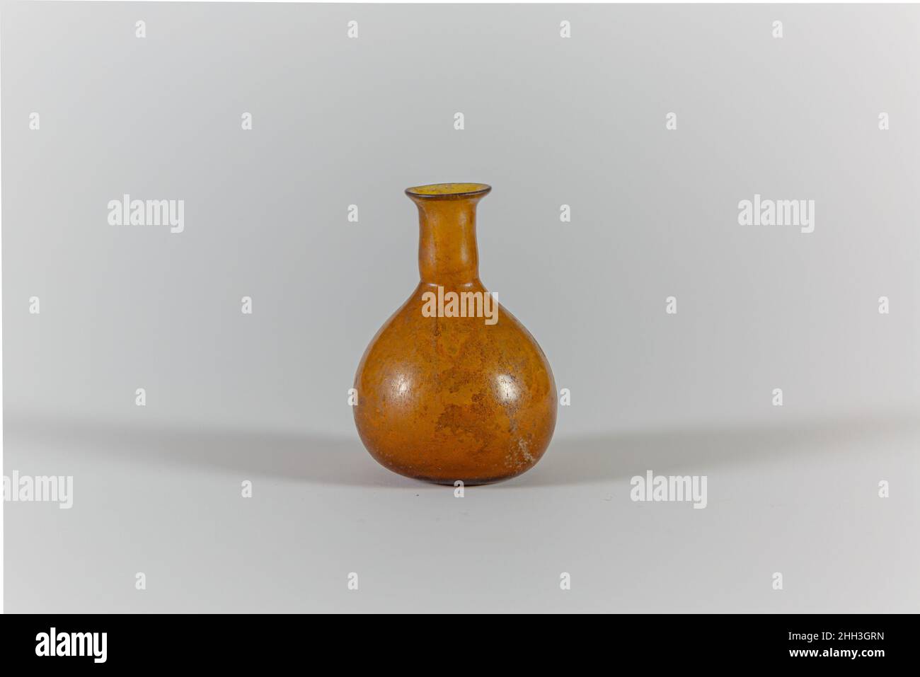 Bottiglia di profumo di vetro metà-1st secolo d.C. romana bordo traslucido giallo.everted del miele con bordo fuoco-arrotondato; collo cilindrico, con margine orizzontale tooled intorno alla base; corpo bulboso; bottom.intact leggermente concavo; alcune bolle del pinprick; dulling, alcuni vaioli, e leggero intemperie su esterno, incrostazione di suolo sul fondo e iridescente intemperie su lato e collo di interno. Bottiglia di profumo in vetro. Romana. Metà del 1st secolo d.C.. Vetro; soffiato. Prima imperiale. Vetro Foto Stock